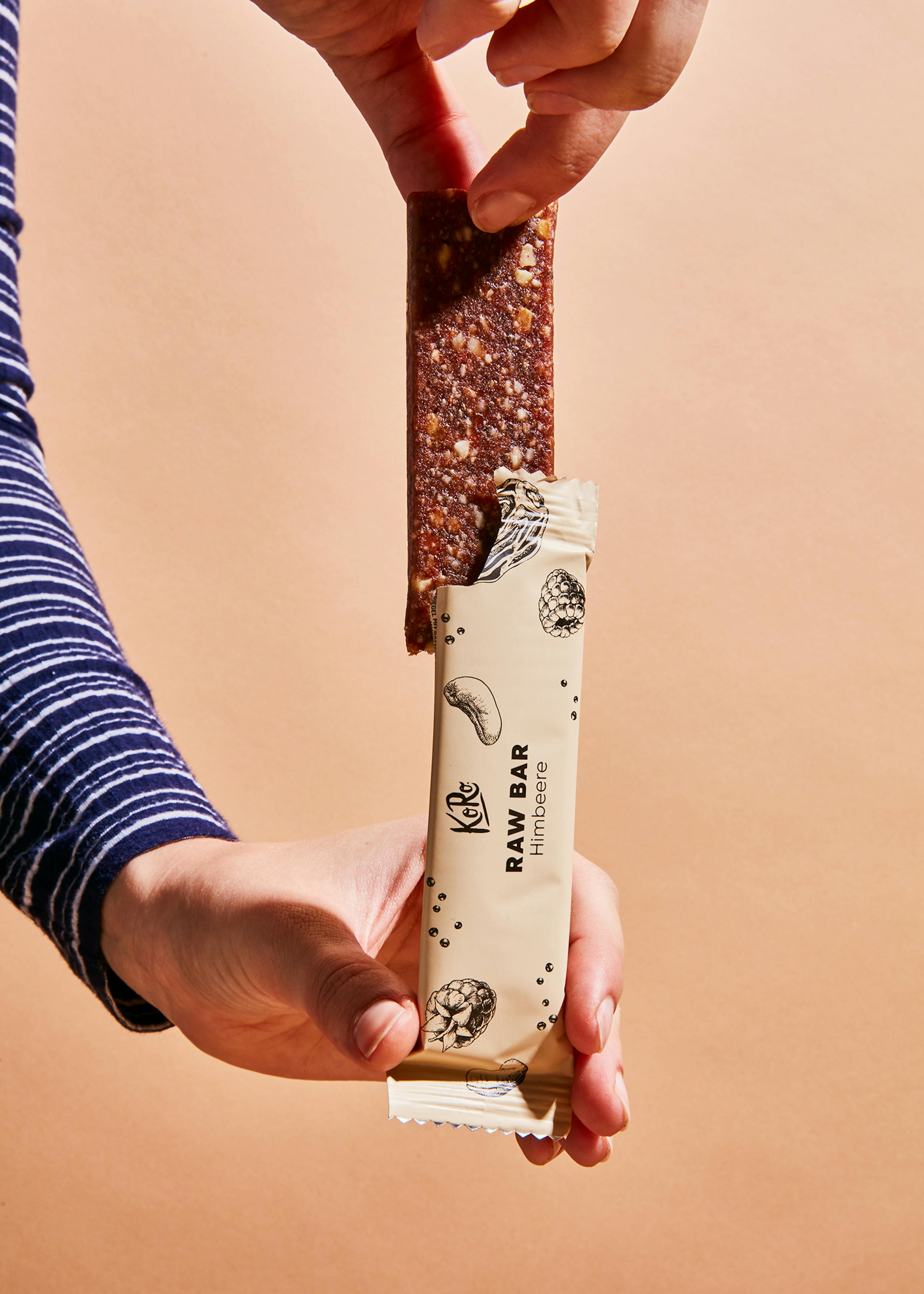 a person is holding a raw bar with a bite taken out of it