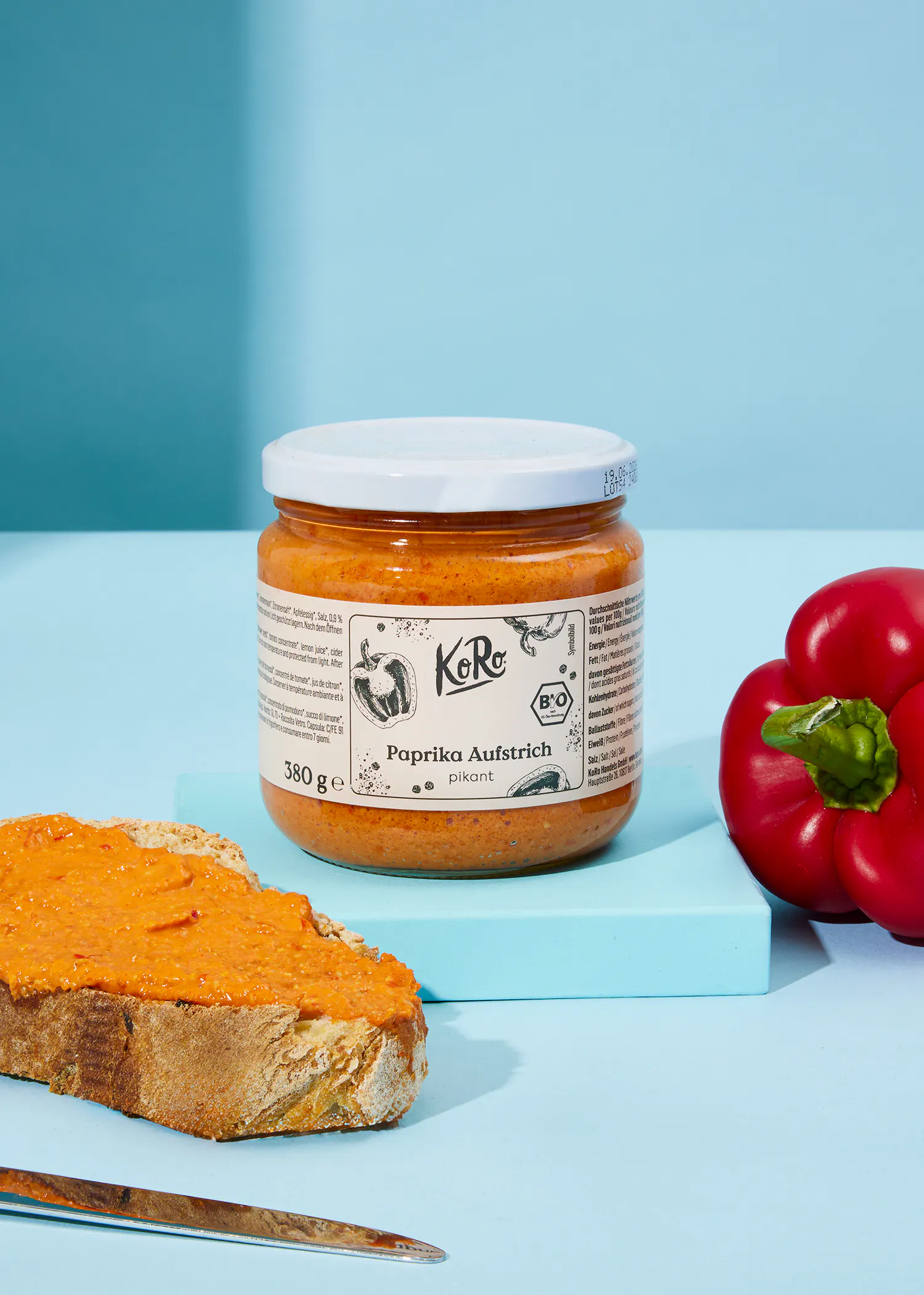 ein Glas paprika aufstrich steht neben einem Stück Brot