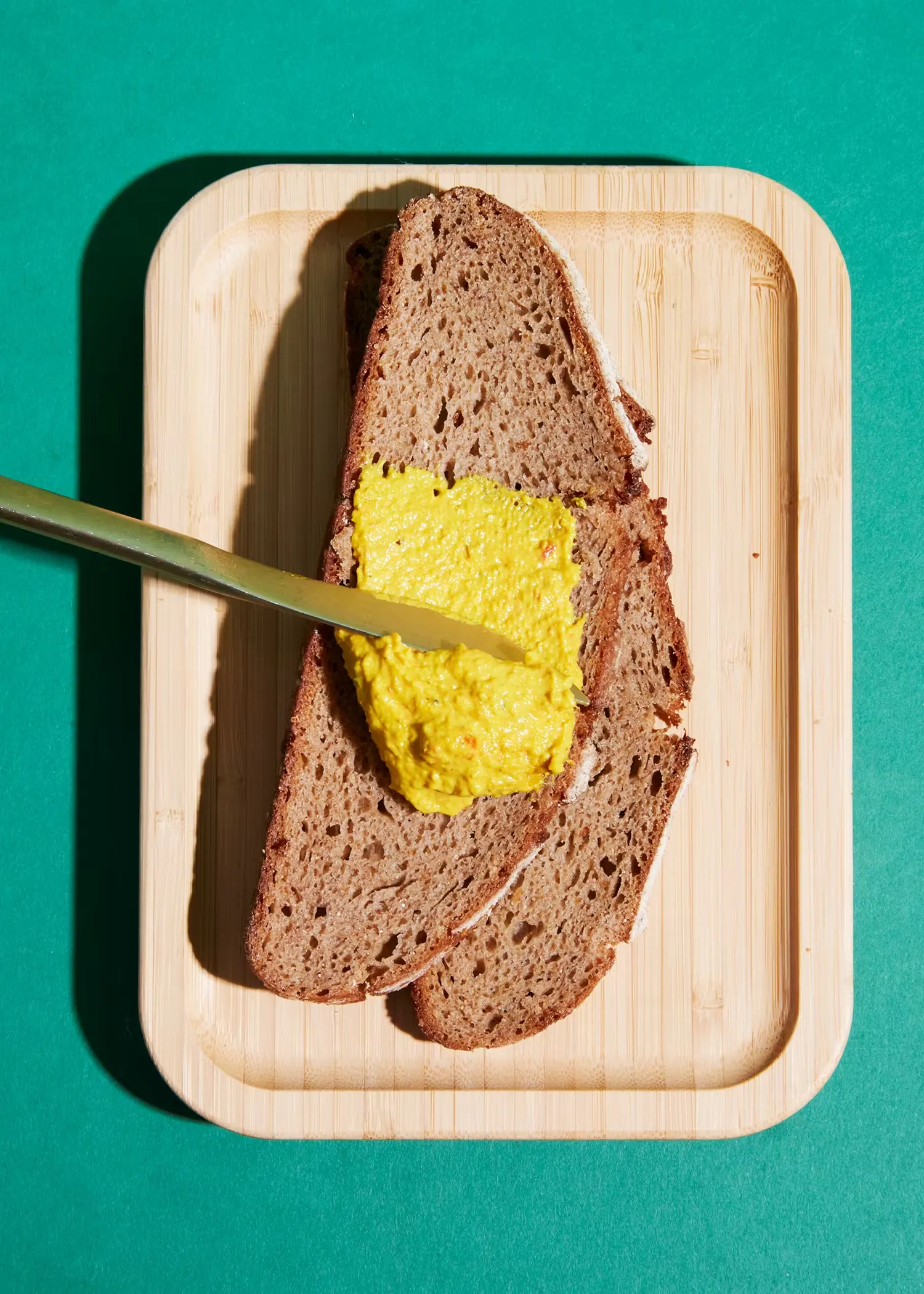 a slice of bread is being spread with yellow mustard