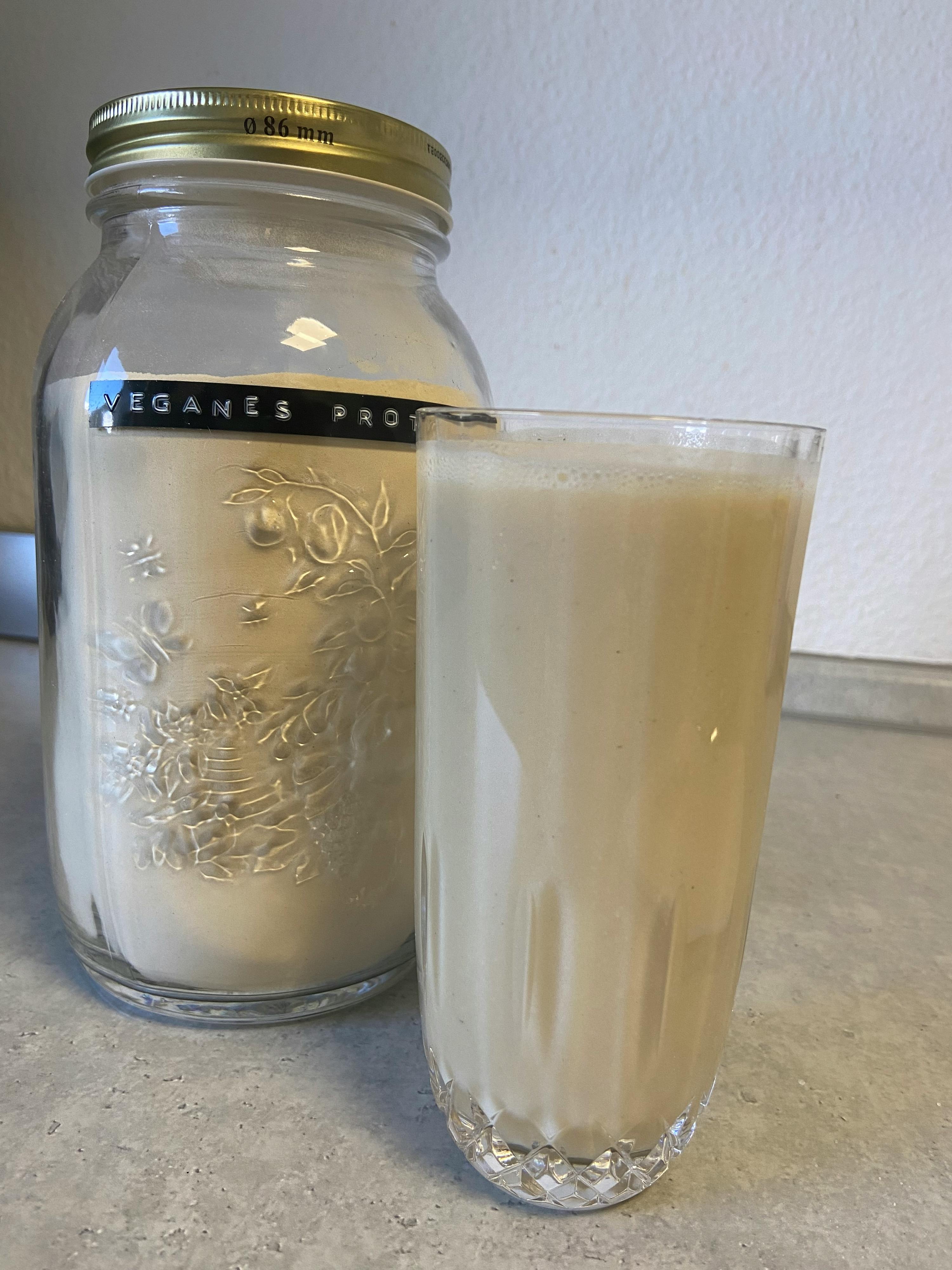 un verre à côté d' un bocal avec une étiquette qui dit veganes pro