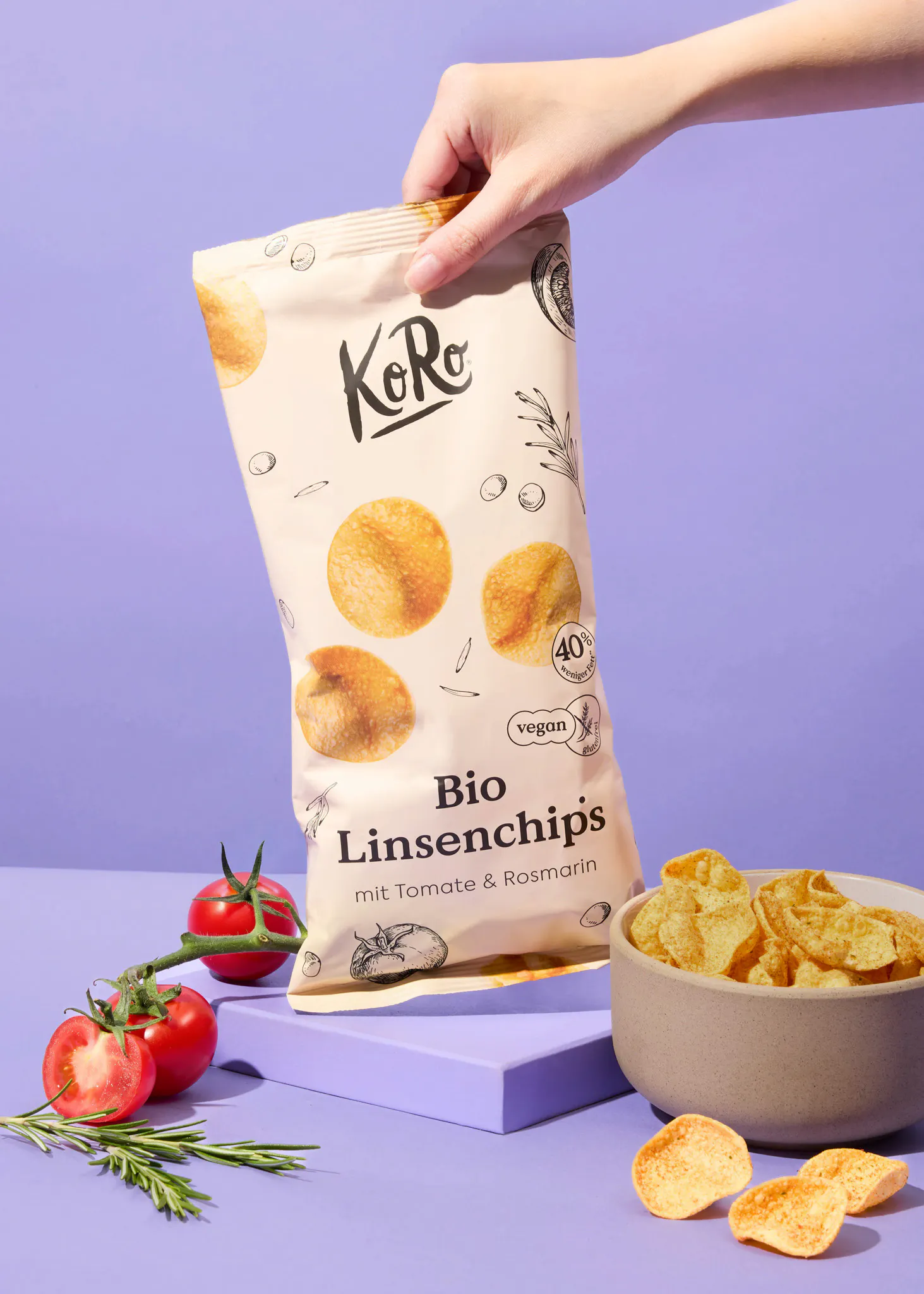 une personne tient un sac de chips bio avec tomates et romarin