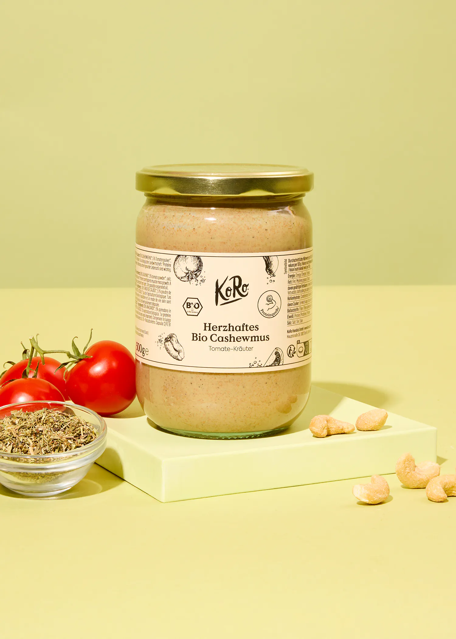 un bocal en verre avec une étiquette blanche à côté d' un bol de tomates et de noix de cajou