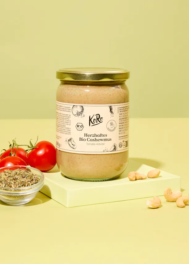 un bocal en verre avec une étiquette blanche à côté d' un bol de tomates et de noix de cajou