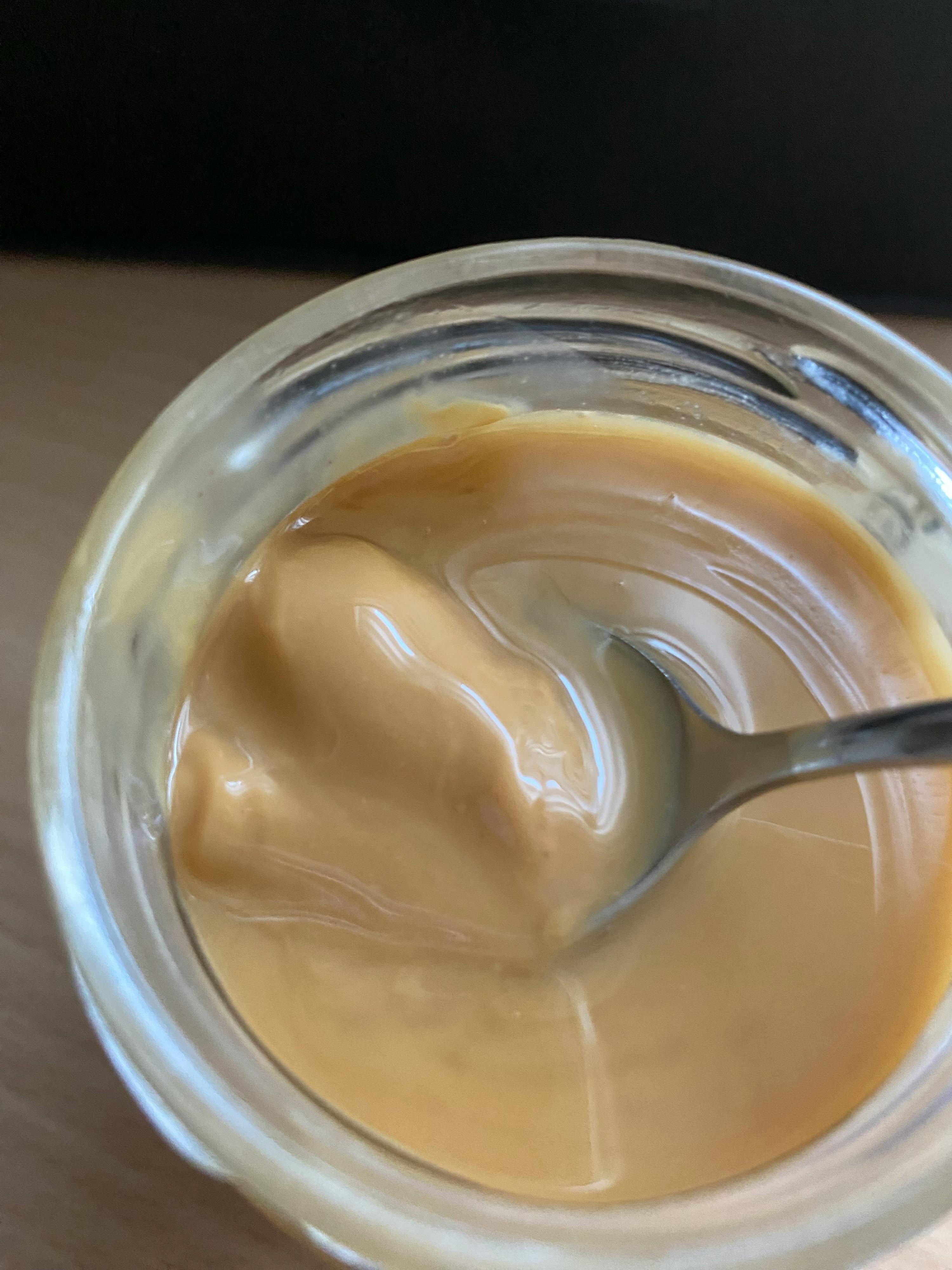 eine Nahaufnahme eines Glases Erdnussbutters mit einem Löffel darin