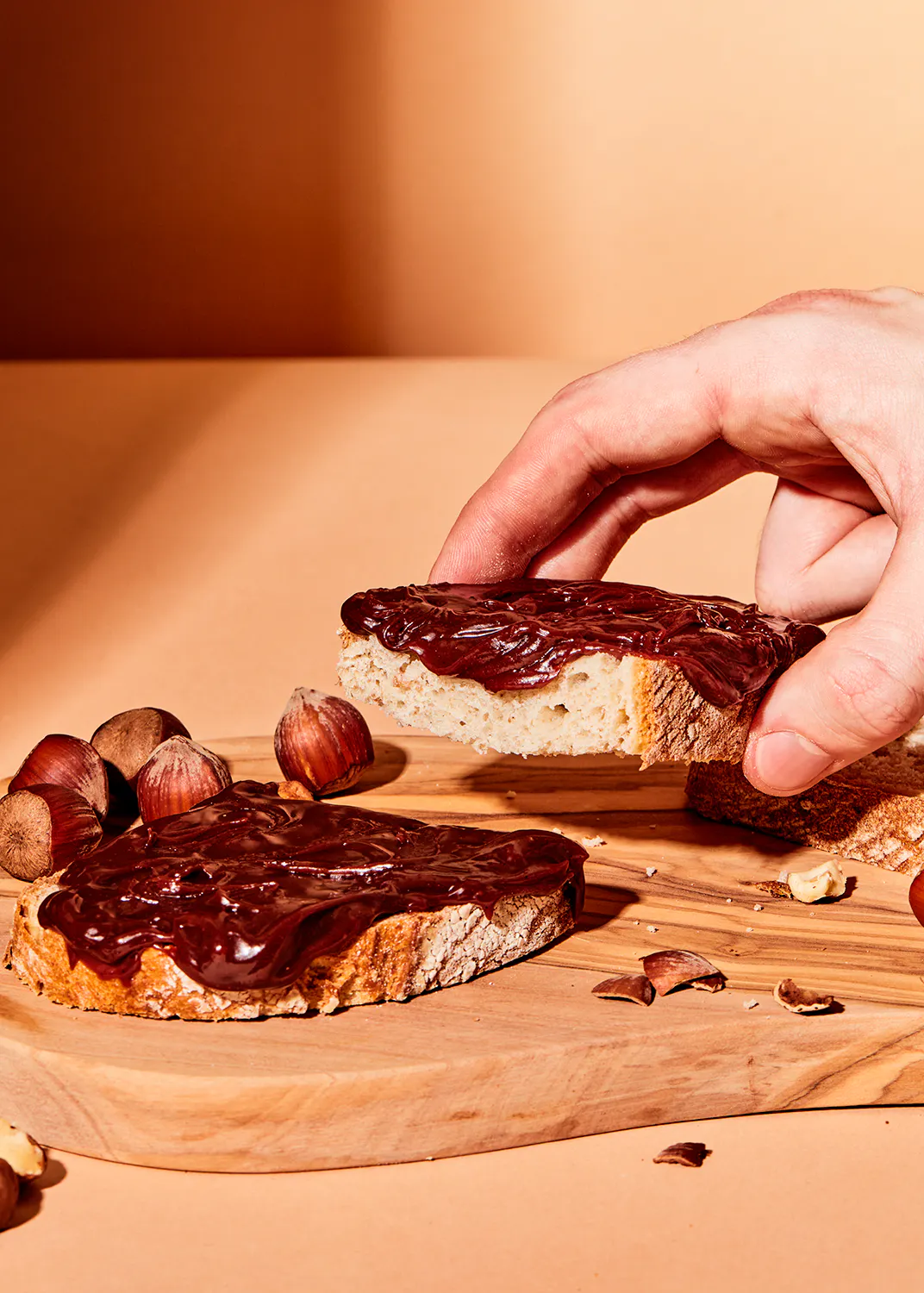 une personne prend une tranche de pain sur une planche à découper en bois