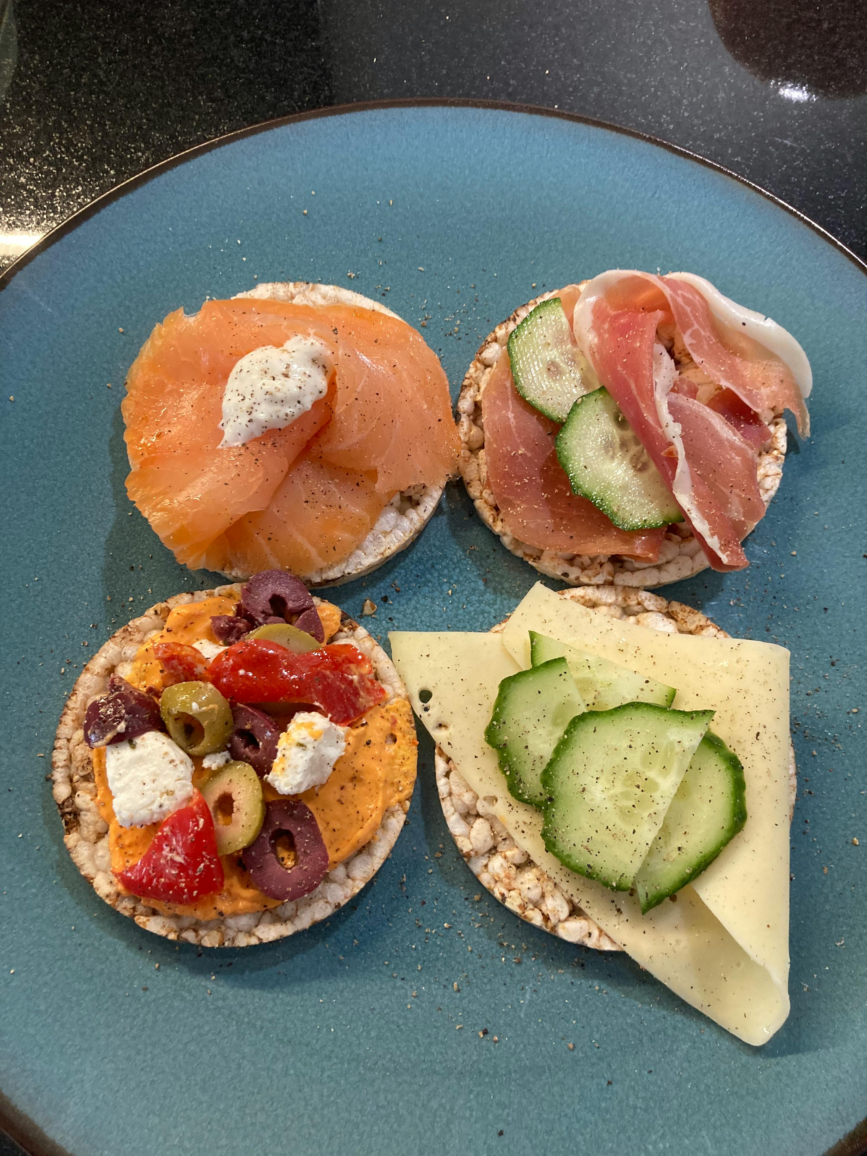 une assiette bleue avec quatre petits pains avec différents types de nourriture sur eux