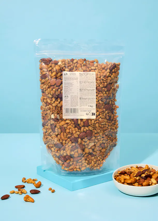 un sac de noix assis sur une table bleue à côté d' un bol de noix