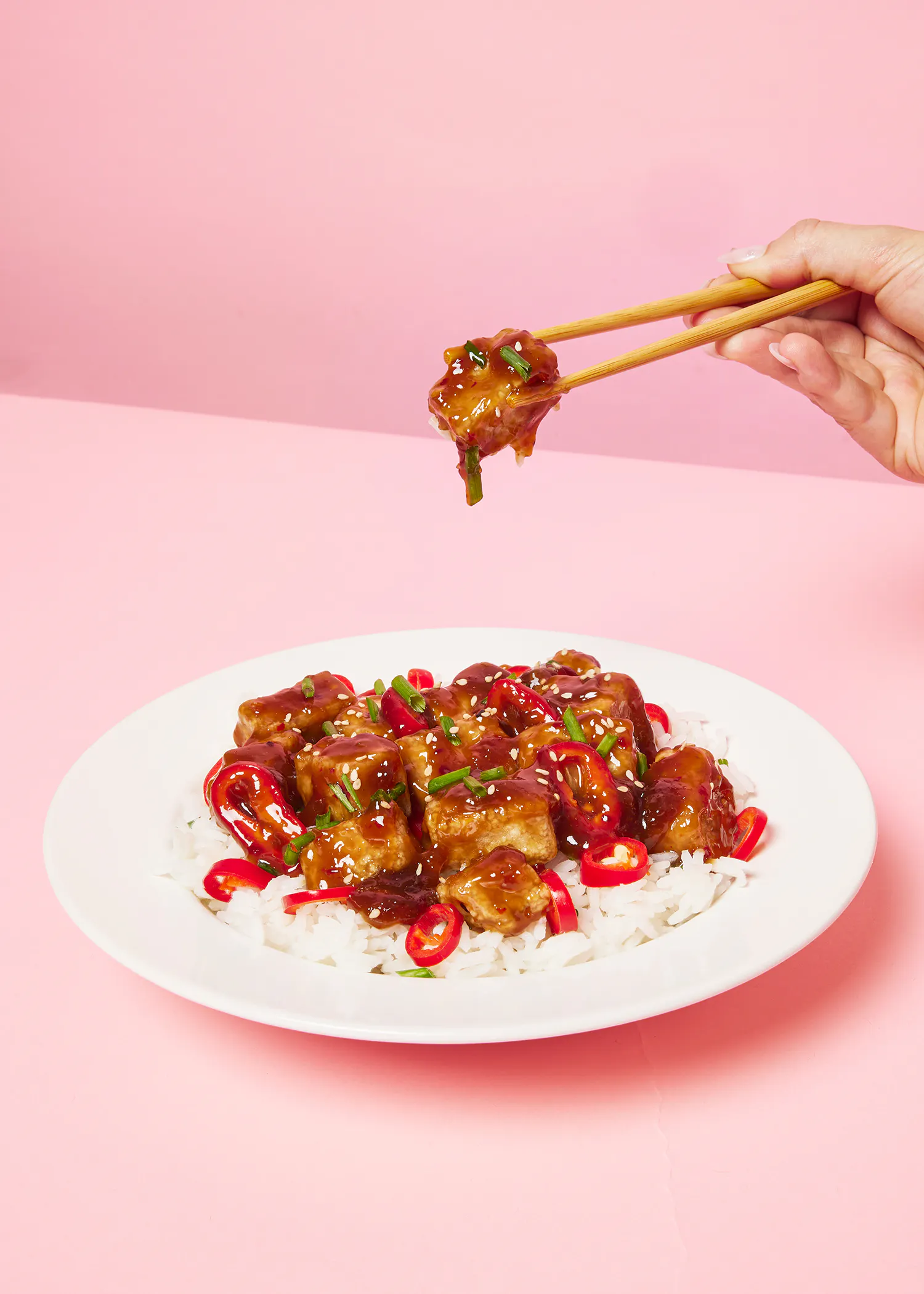 une personne prend un morceau de nourriture avec des baguettes