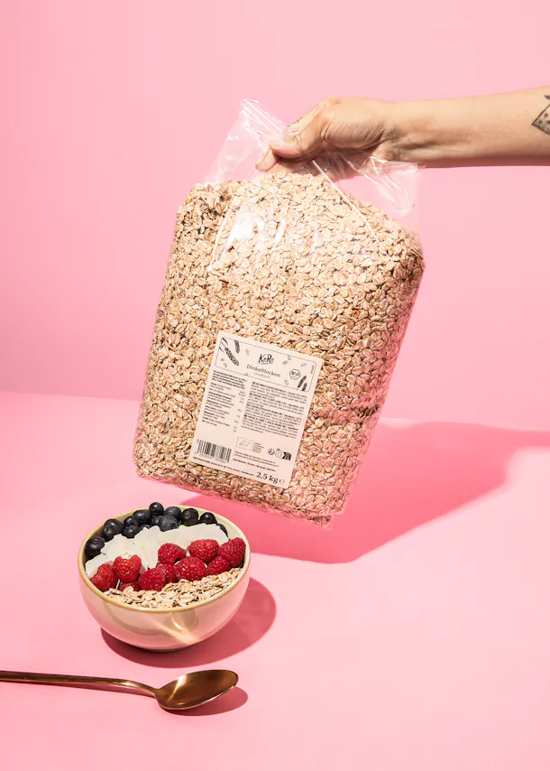 a person is holding a bag of oats over a bowl of cereal