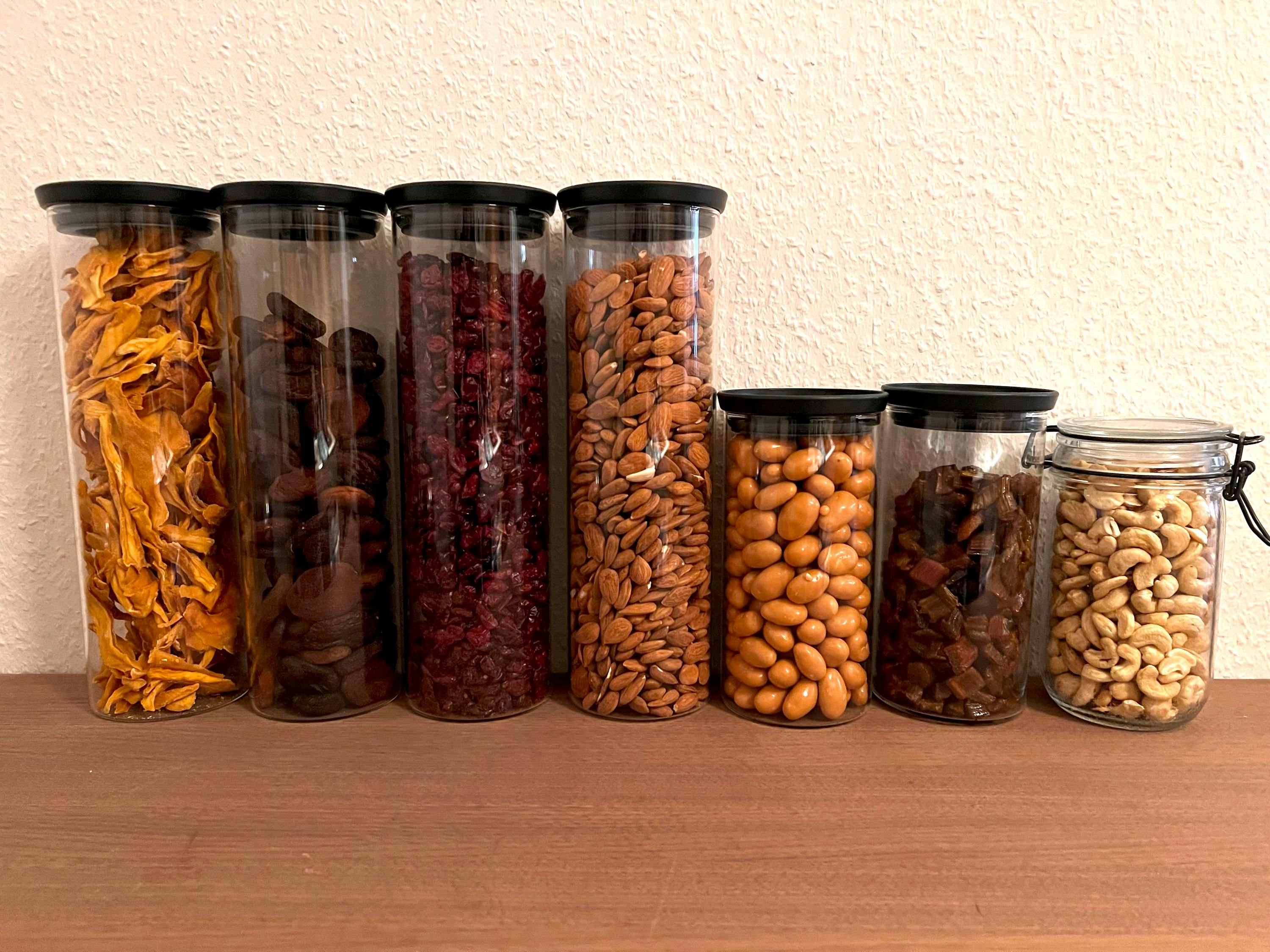 un tas de bocaux remplis de différents types de noix et de fruits secs