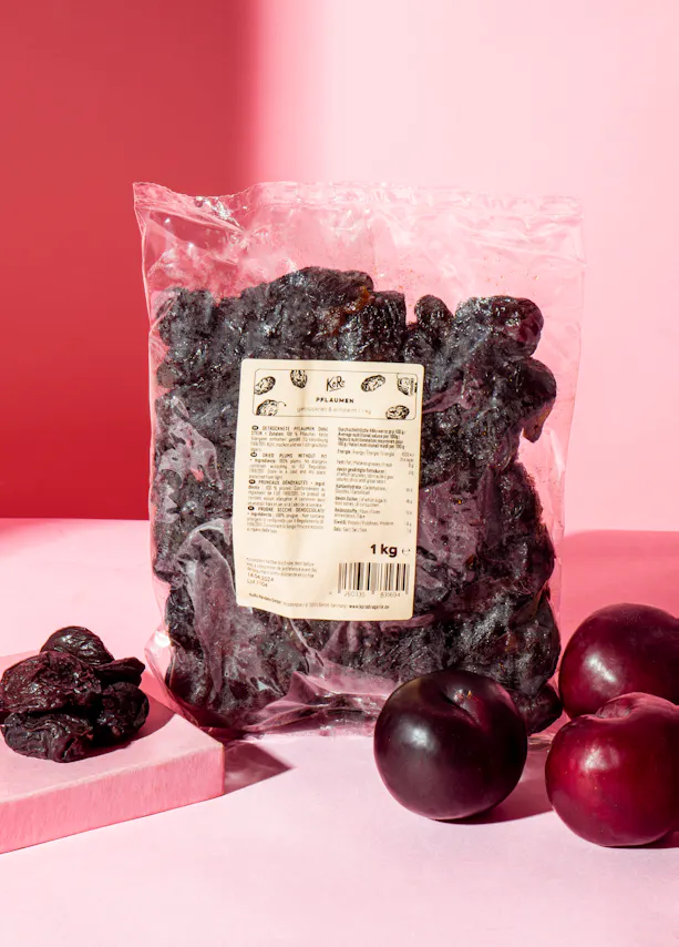 un sac de prunes séchées est assis sur une table rose