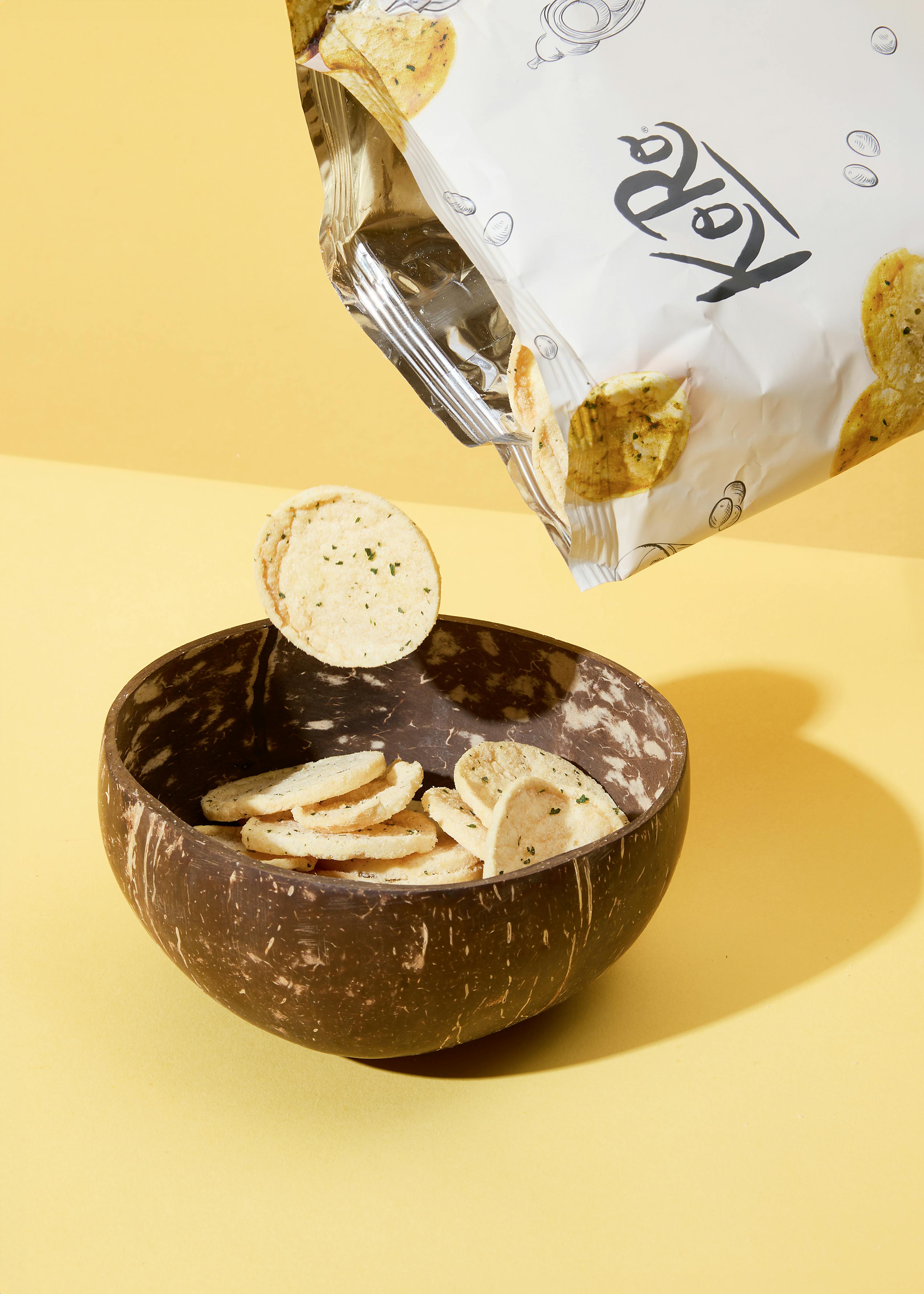 eine Tüte Kartoffelchips fällt in eine Kokosnussschale