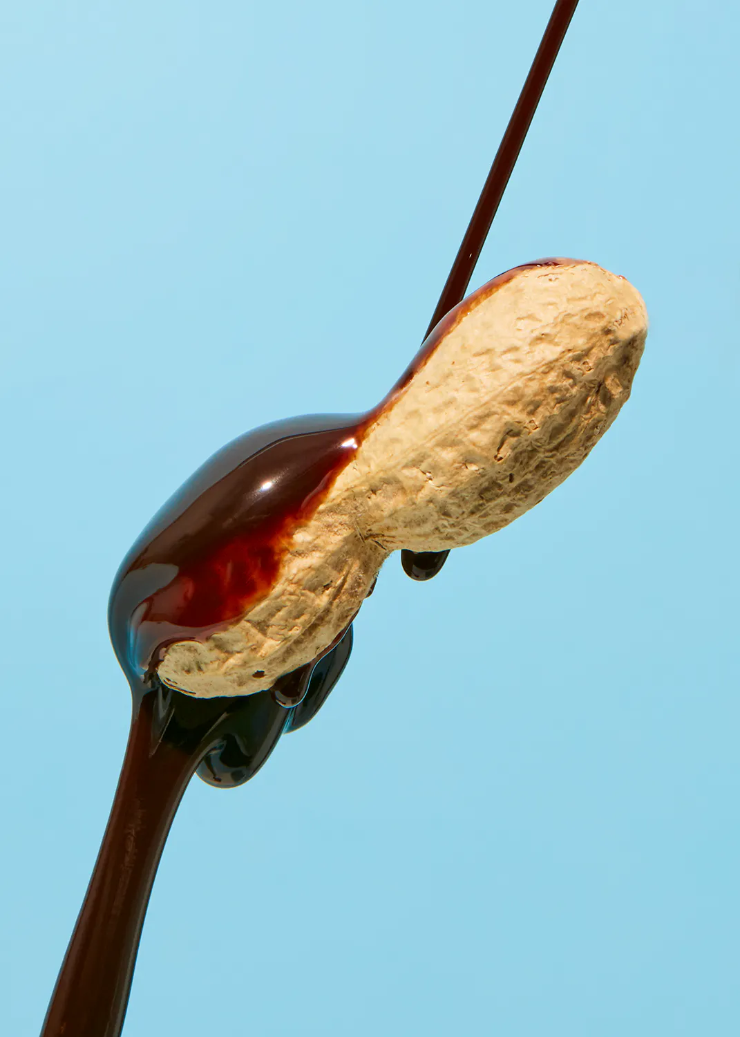 a peanut is being covered in chocolate on a blue background