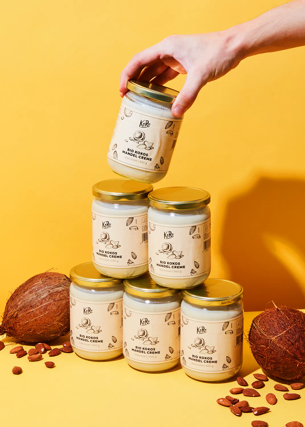 Eine Person hält ein Glas Bio-Kokos-Mandelcreme in der Hand