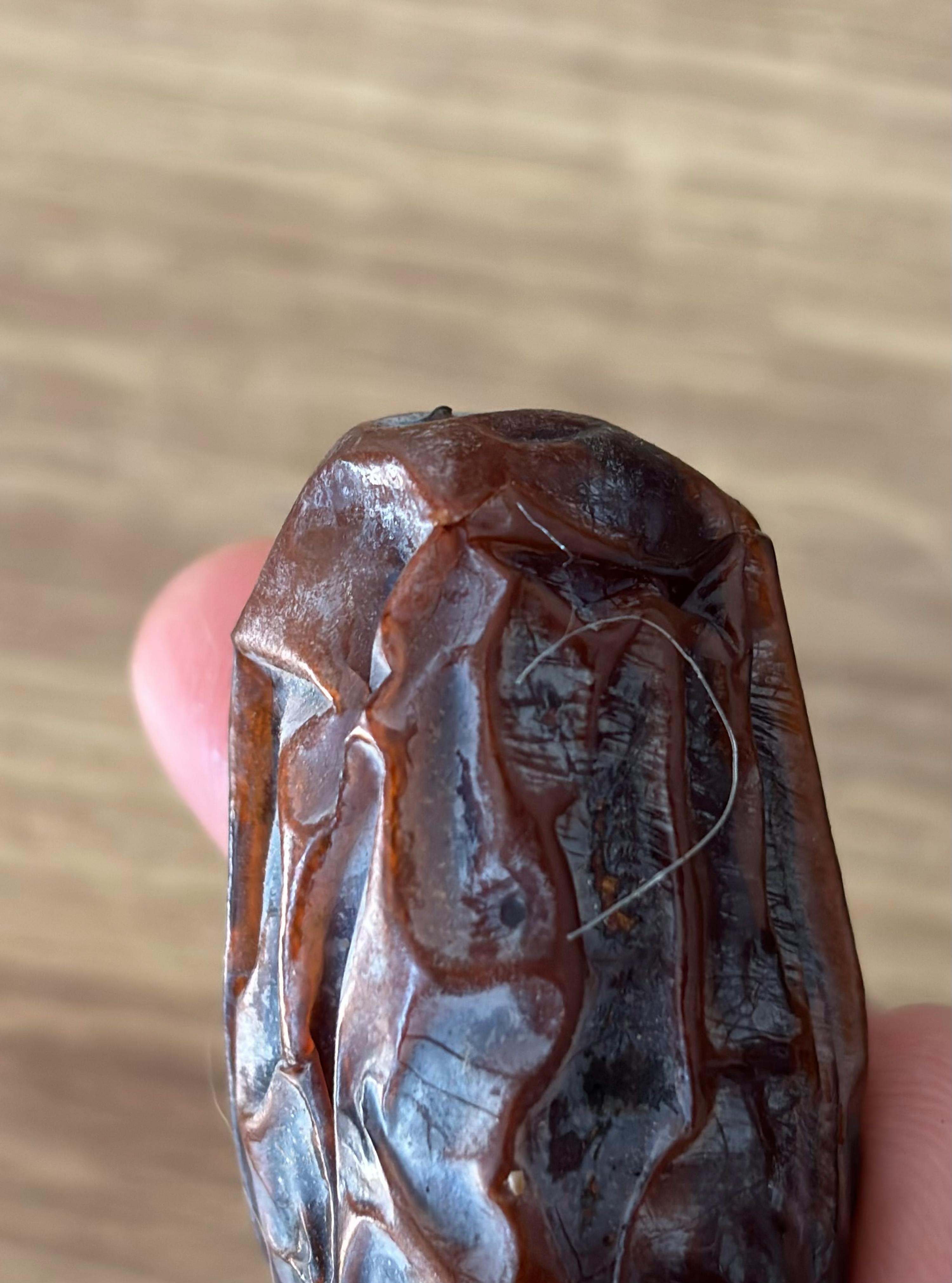 a person is holding a brown item with a string coming out of it