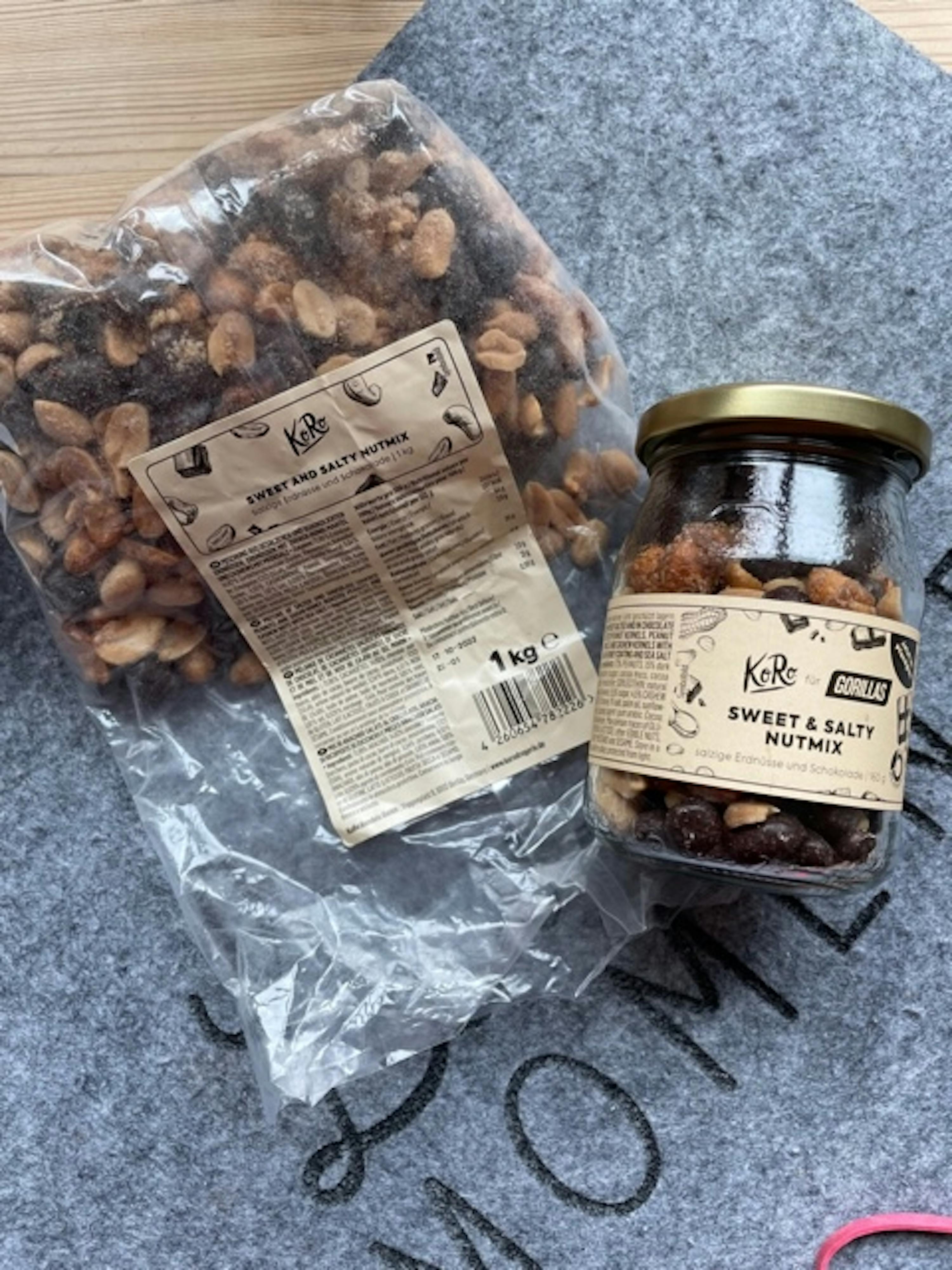 eine Tüte gerösteter Erdnüsse liegt neben einem Glas gerösteter Erdnüsse