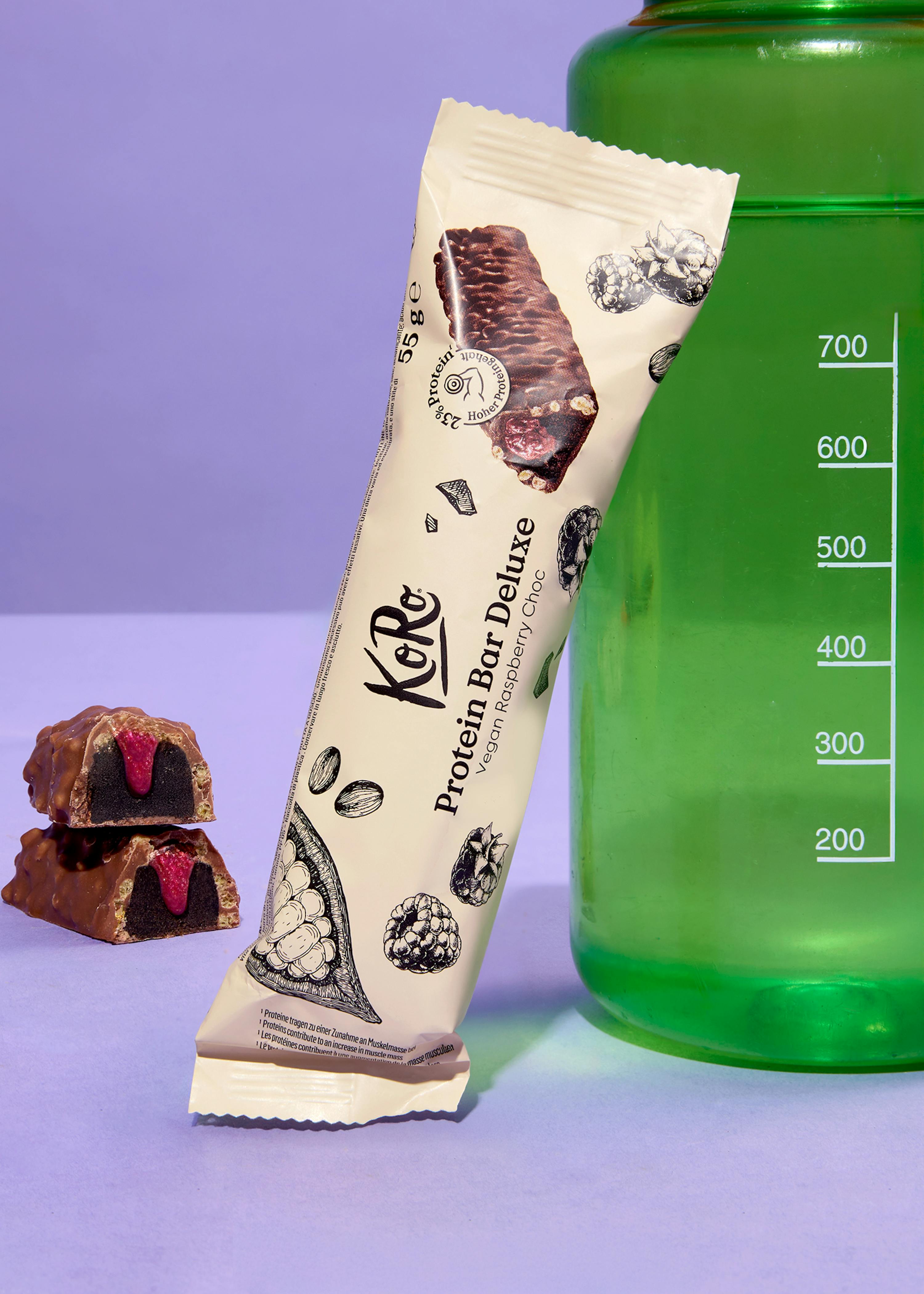 una barretta di proteine con lampone e cioccolato è seduta accanto a una bottiglia di acqua verde