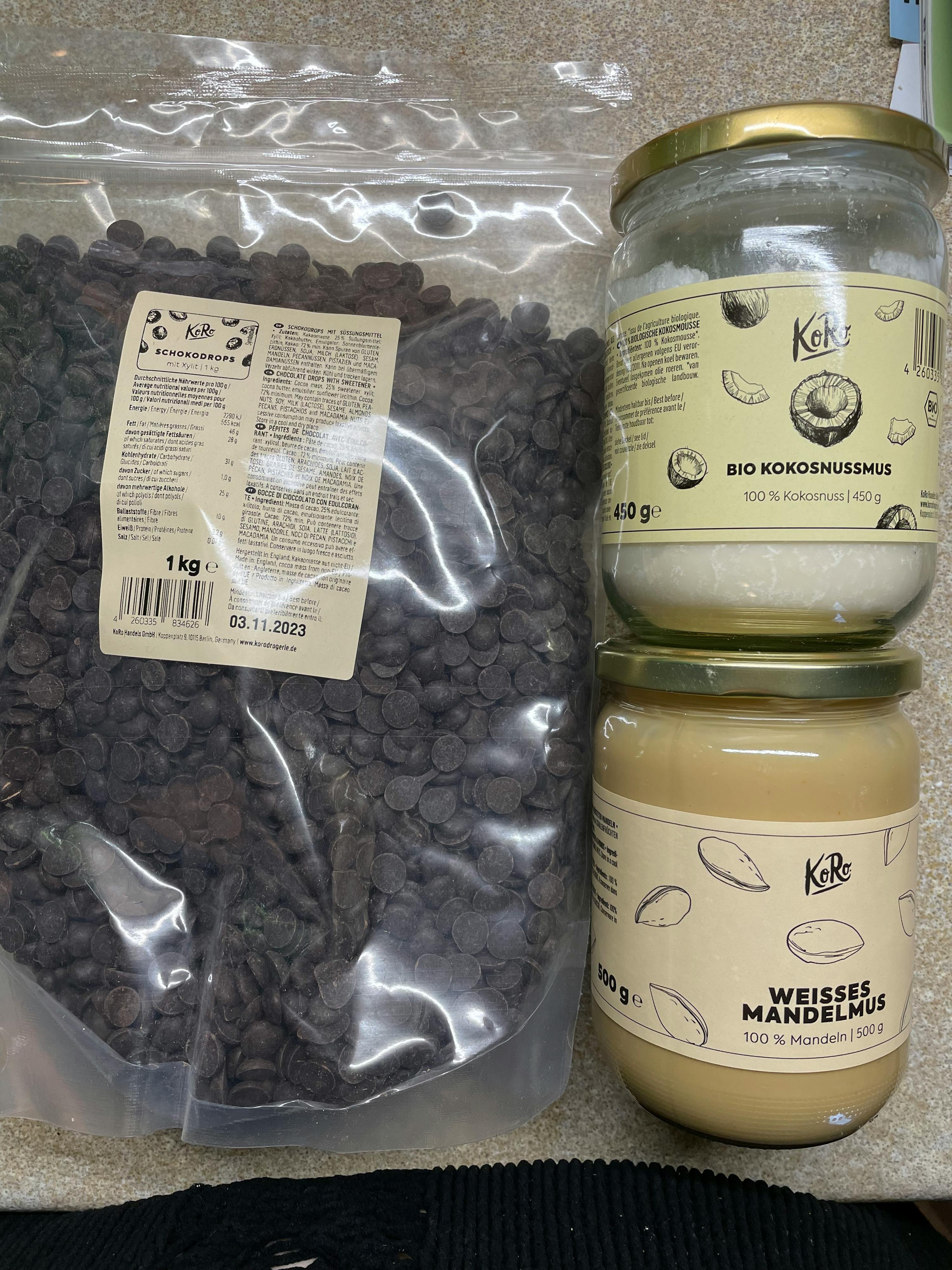 a bag of chocolate chips sits next to a jar of coconut oil and a jar of mandelmus