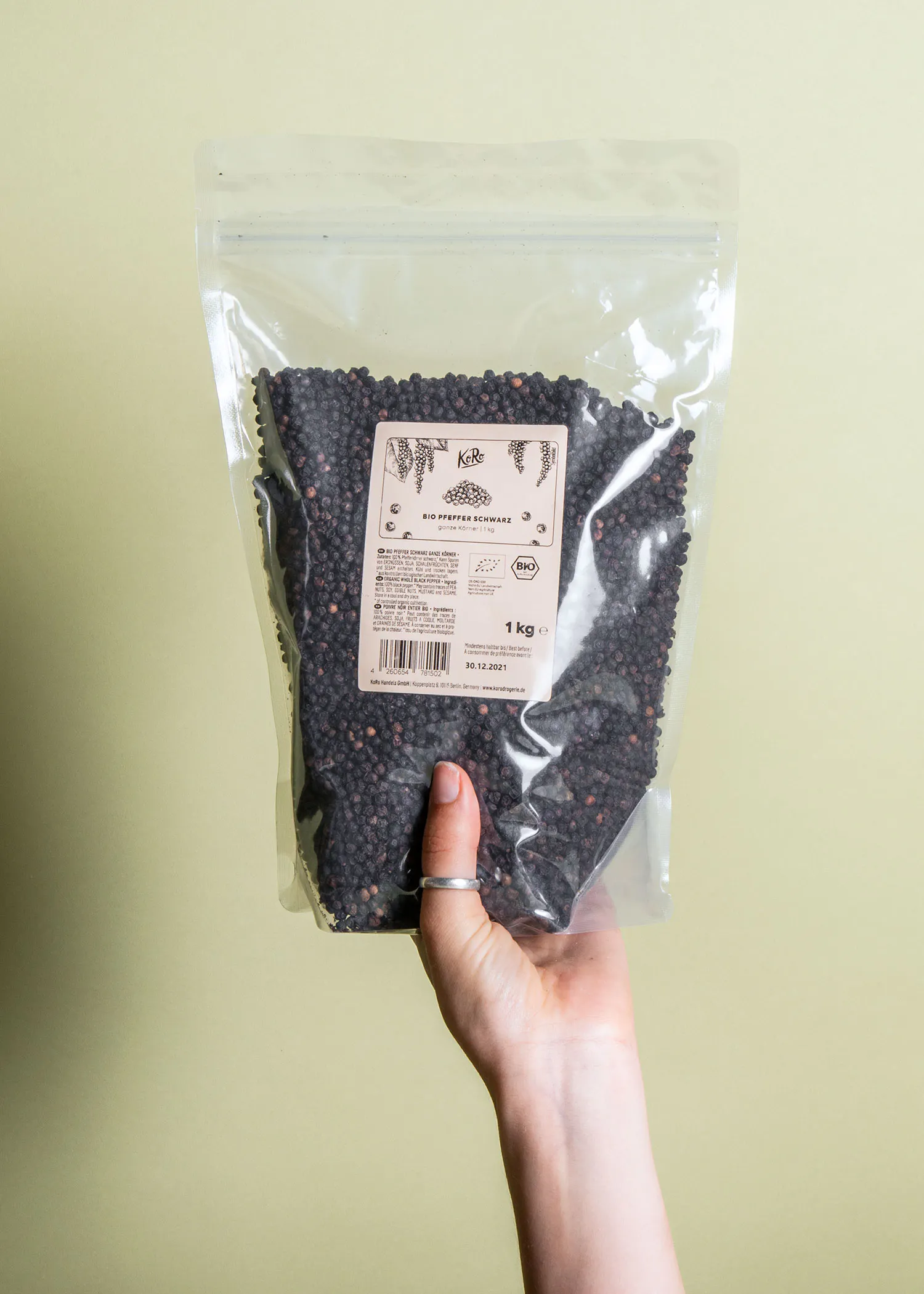 une personne tient un sac de graines de poivre noir biologique