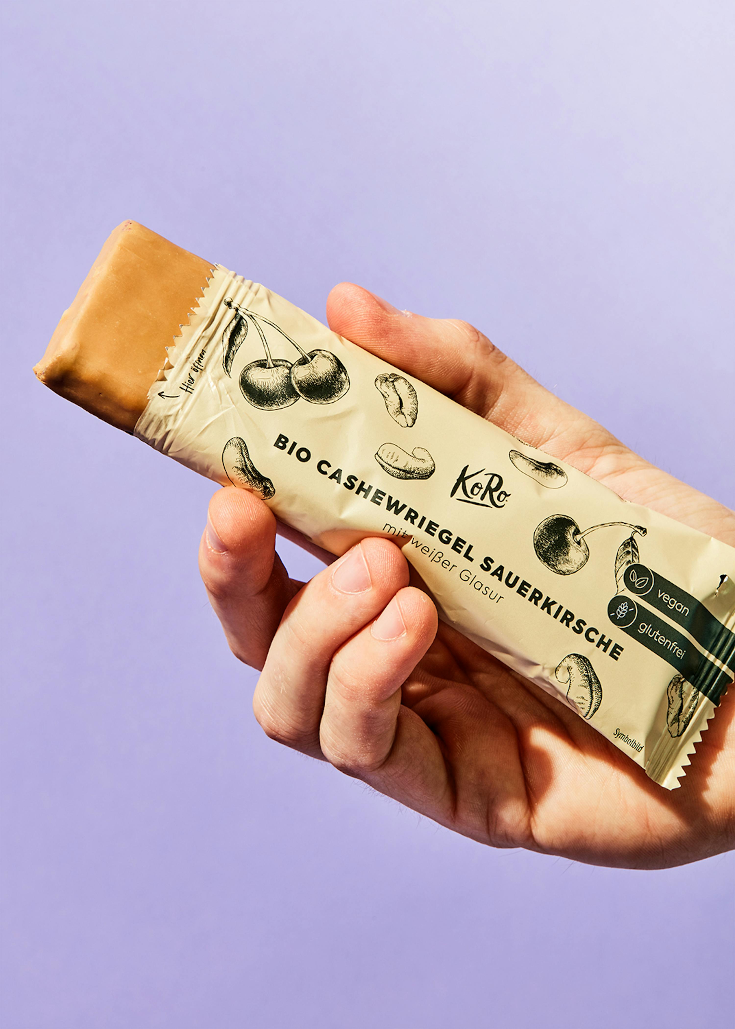 une personne tient une barre de chocolat bio avec des noix de cajou