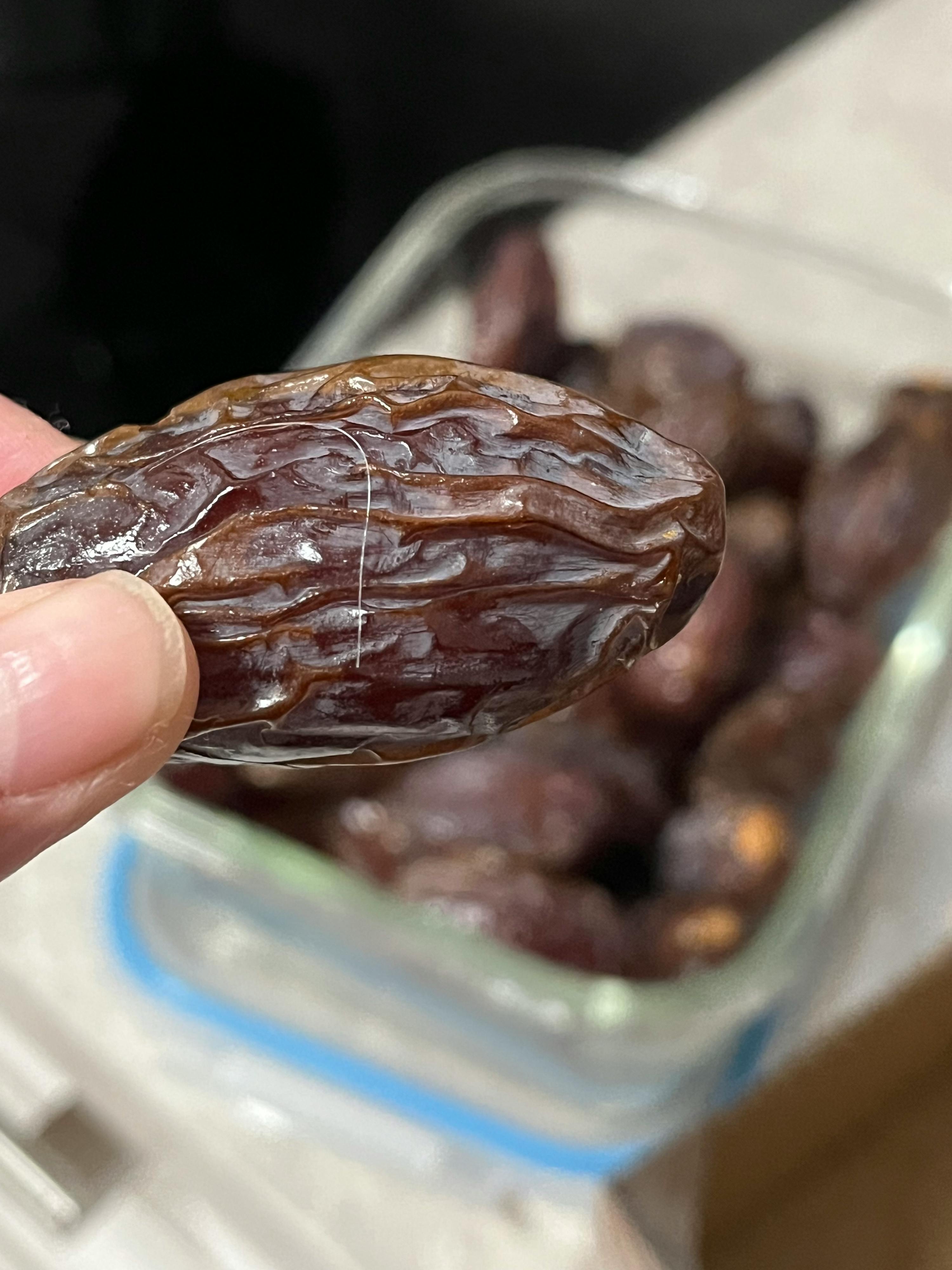 un gros plan d' une main tenant une datte