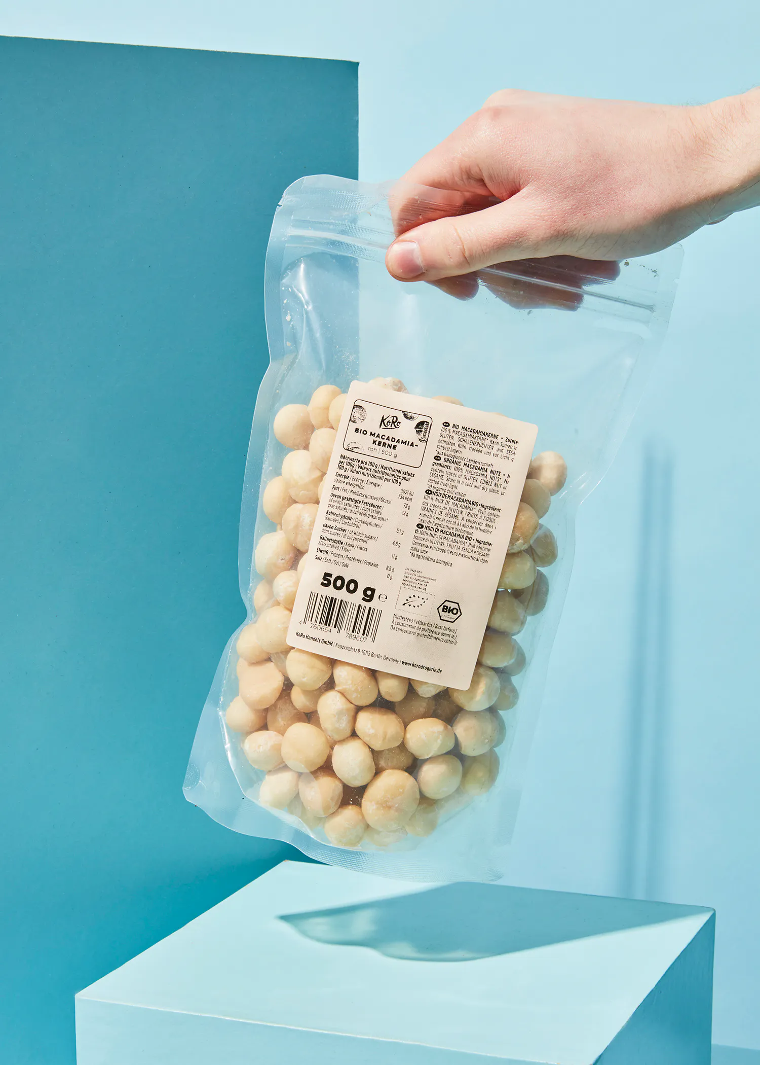 une personne tient un sac de noix de macadamia 500g
