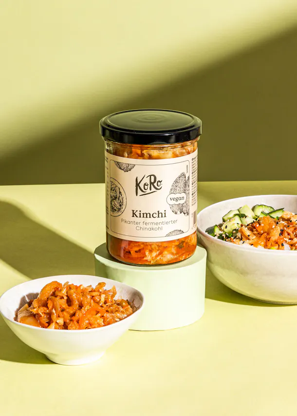 un pot de kimchi est assis sur une table à côté d' un bol de nourriture