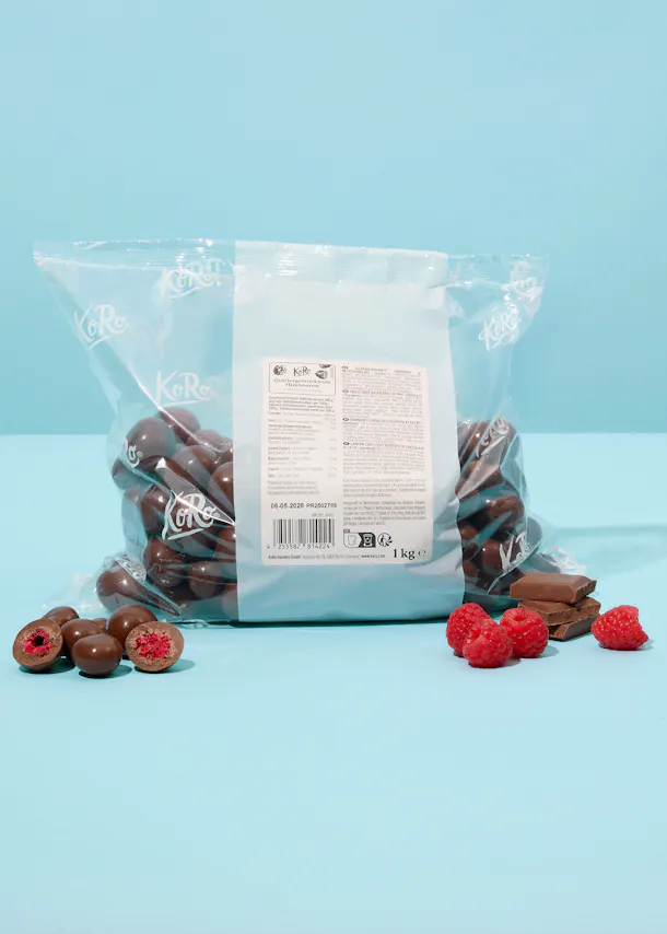 a bag of chocolate covered raspberries sits on a blue table