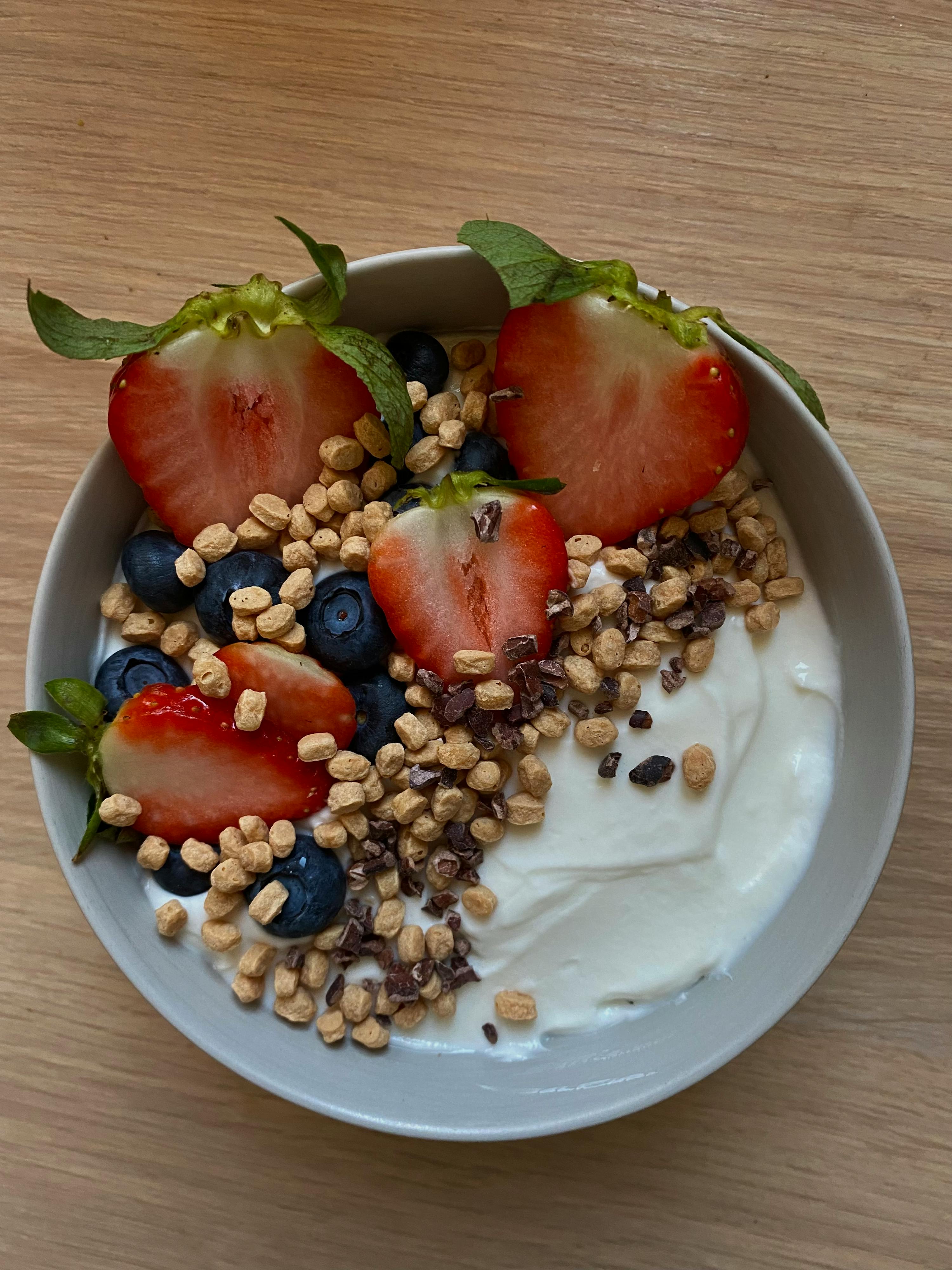 un bol de yogourt avec des fraises et des myrtilles