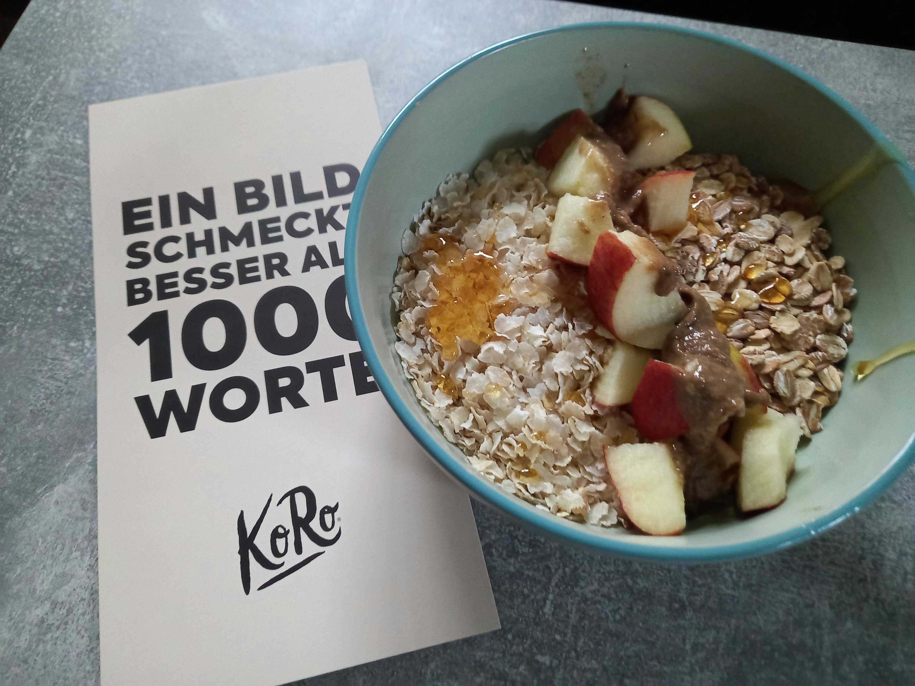 un bol d' avoine avec des pommes et du miel est assis à côté d' une brochure avec 1000 mots