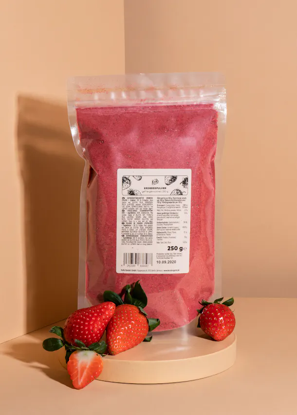 un sac de poudre de fraise est posé sur une table avec des fraises