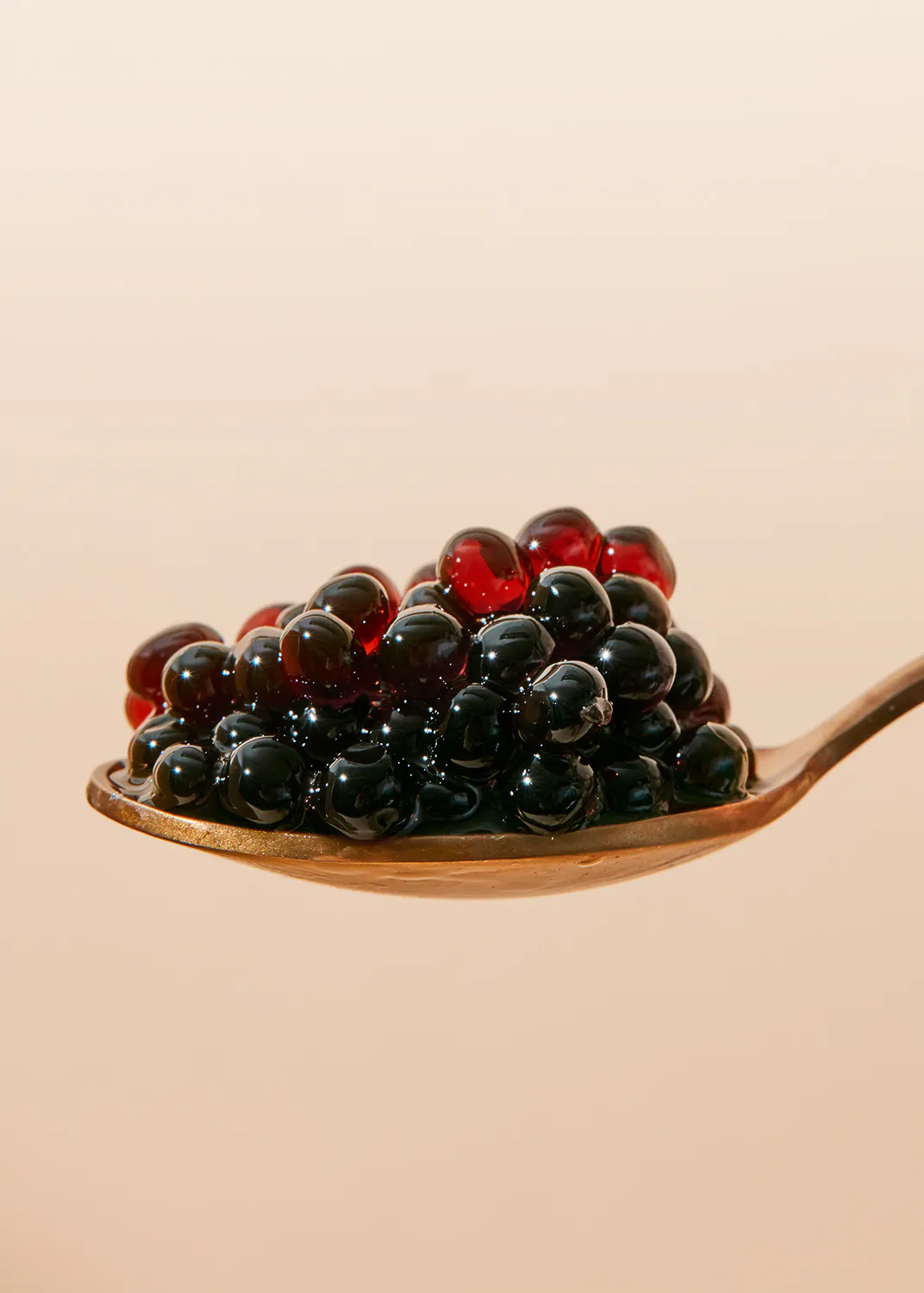 a gold spoon filled with black and red pills