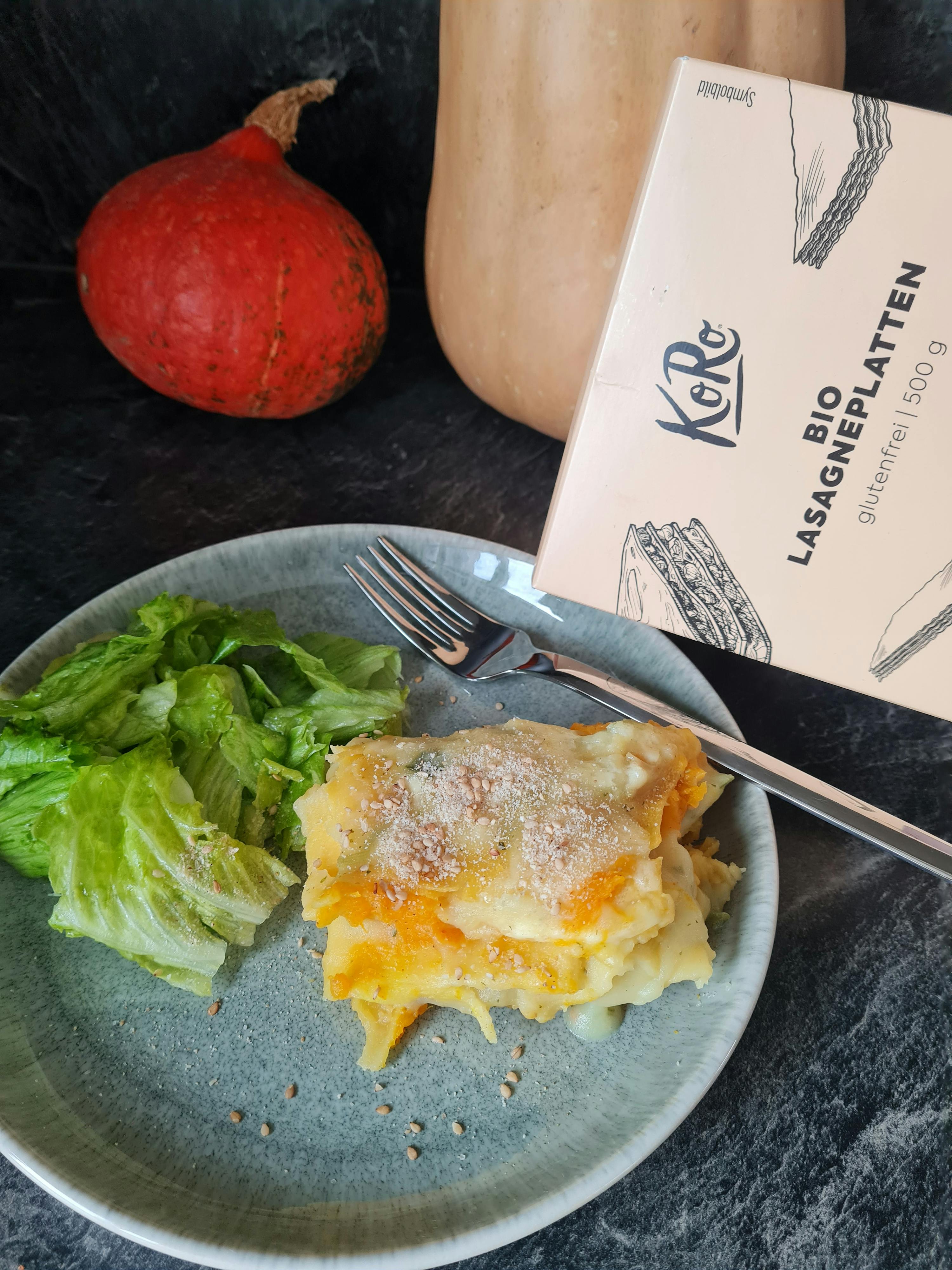 une assiette de nourriture avec une fourchette à côté d' une boîte de lasagneplatten bio