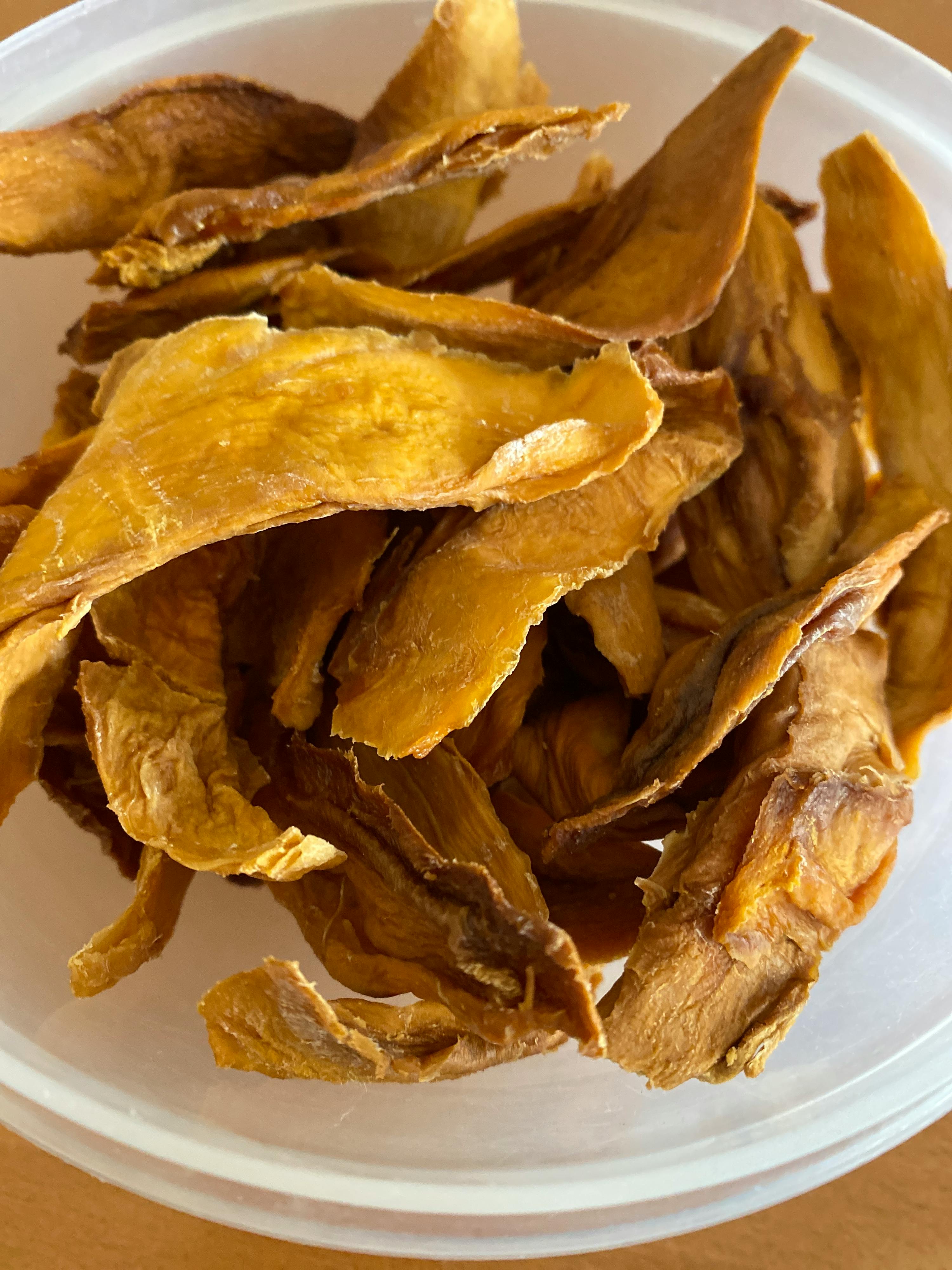 un bol en plastique rempli de tranches de mangue séchées