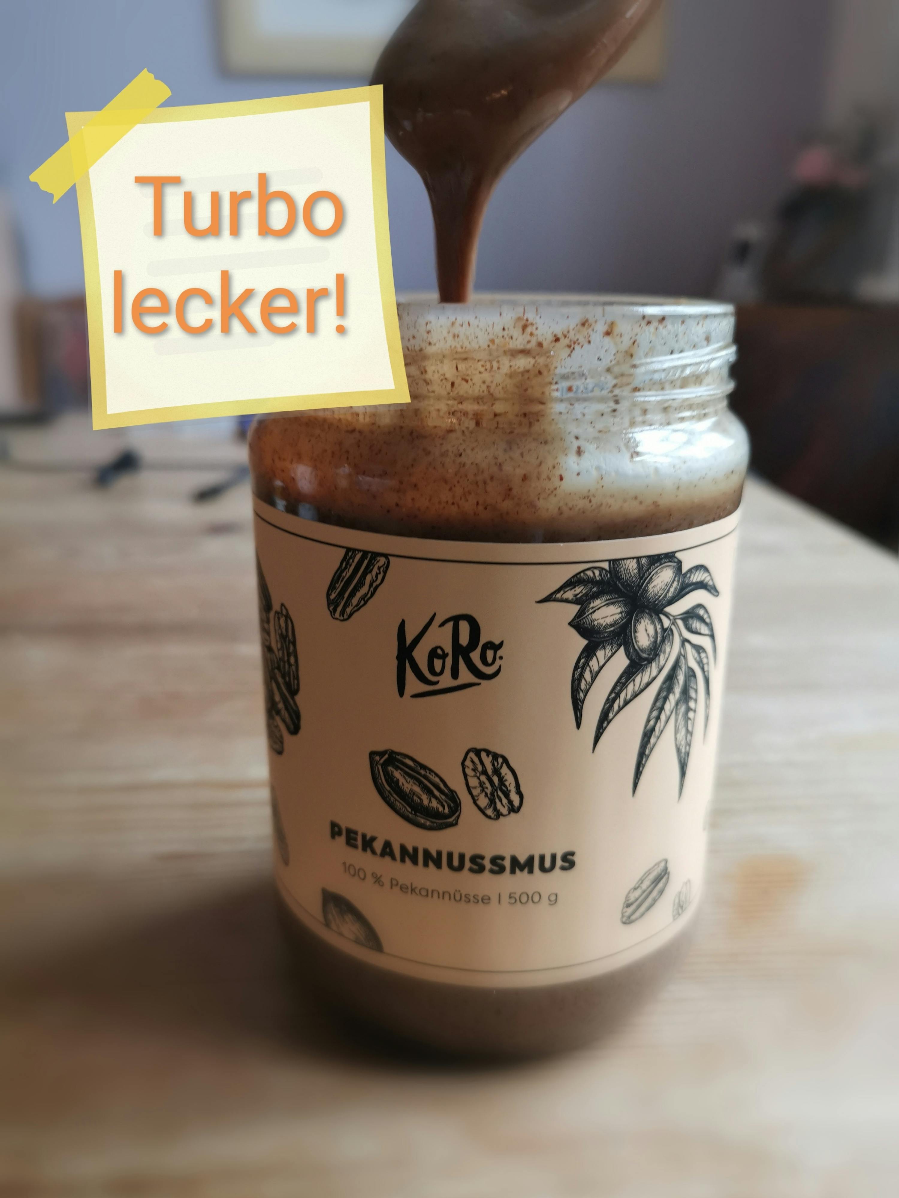 a jar of koro pekannussmus is being poured with a spoon