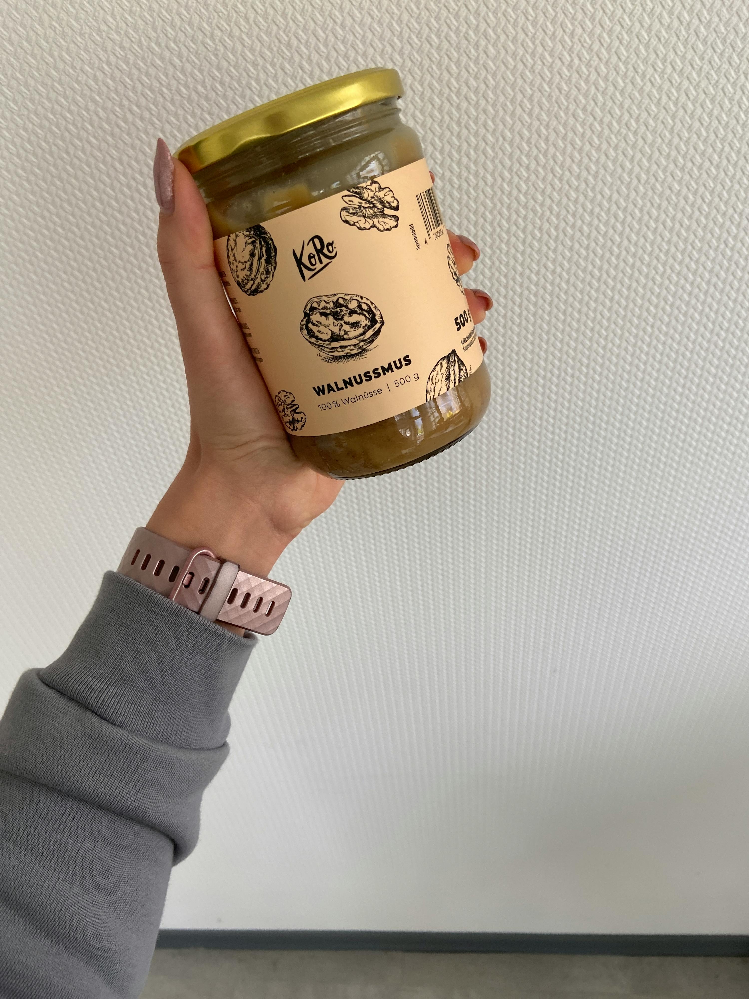 a woman is holding a jar of walnut spread