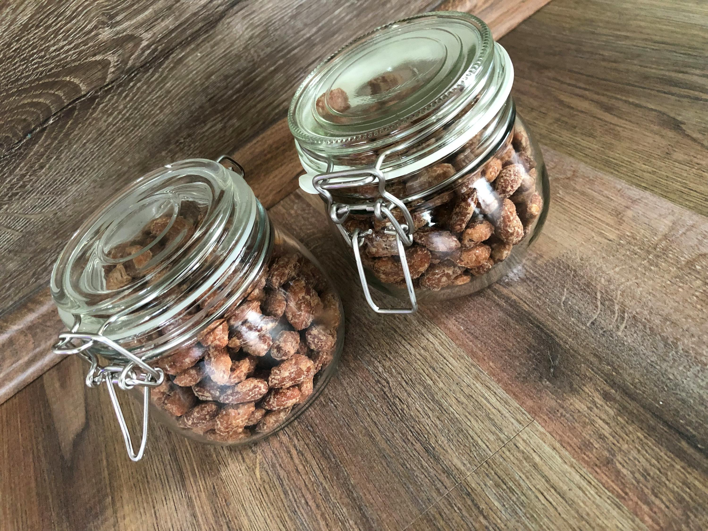 deux bocaux en verre remplis de noix sur une surface en bois