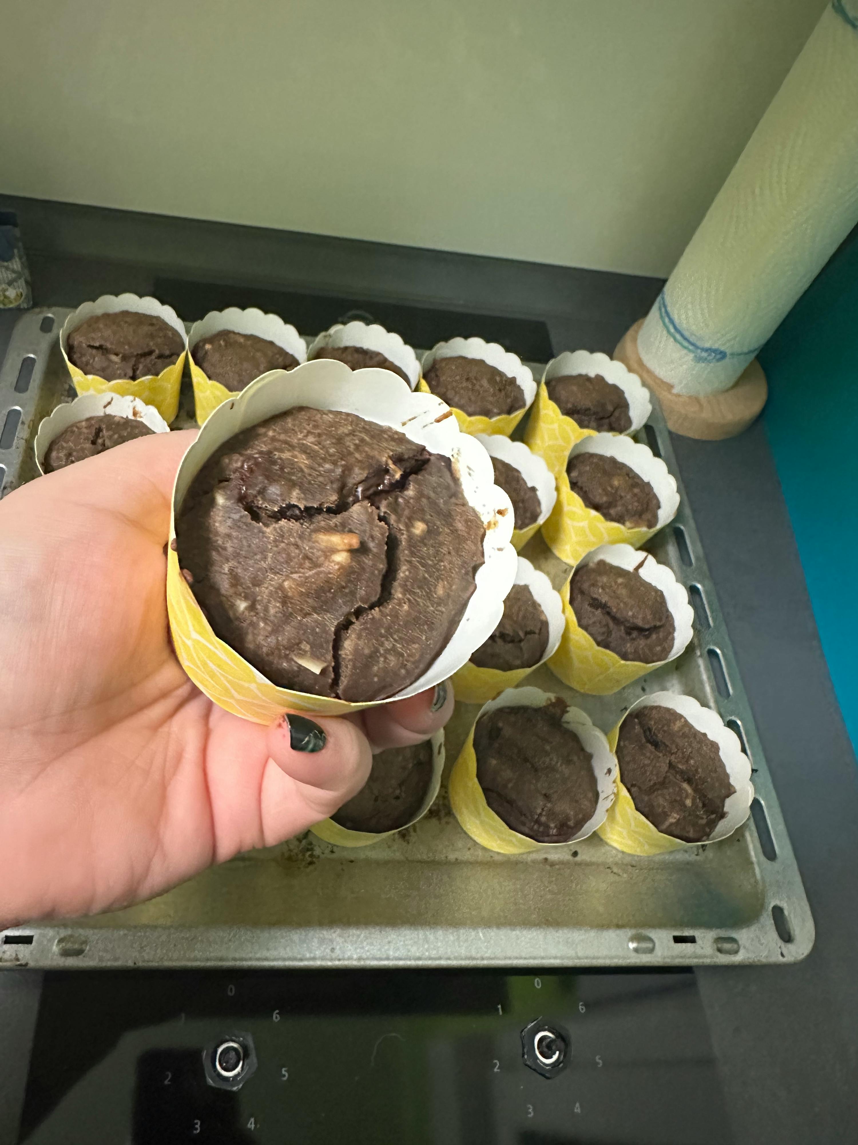 a person is holding a brownie in front of a tray of brownies