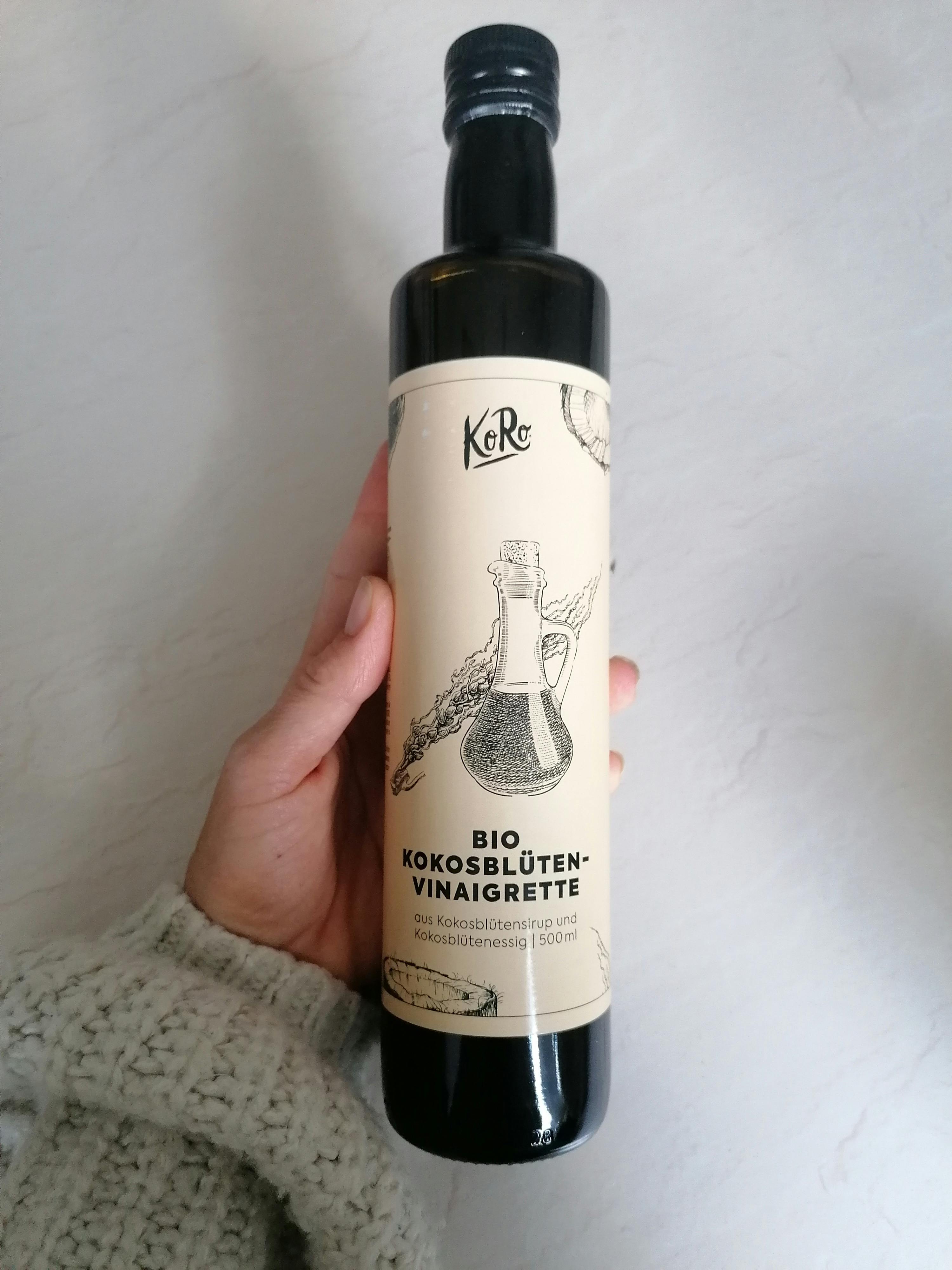 a person is holding a bottle of bio kokosblumen-vinaigrette