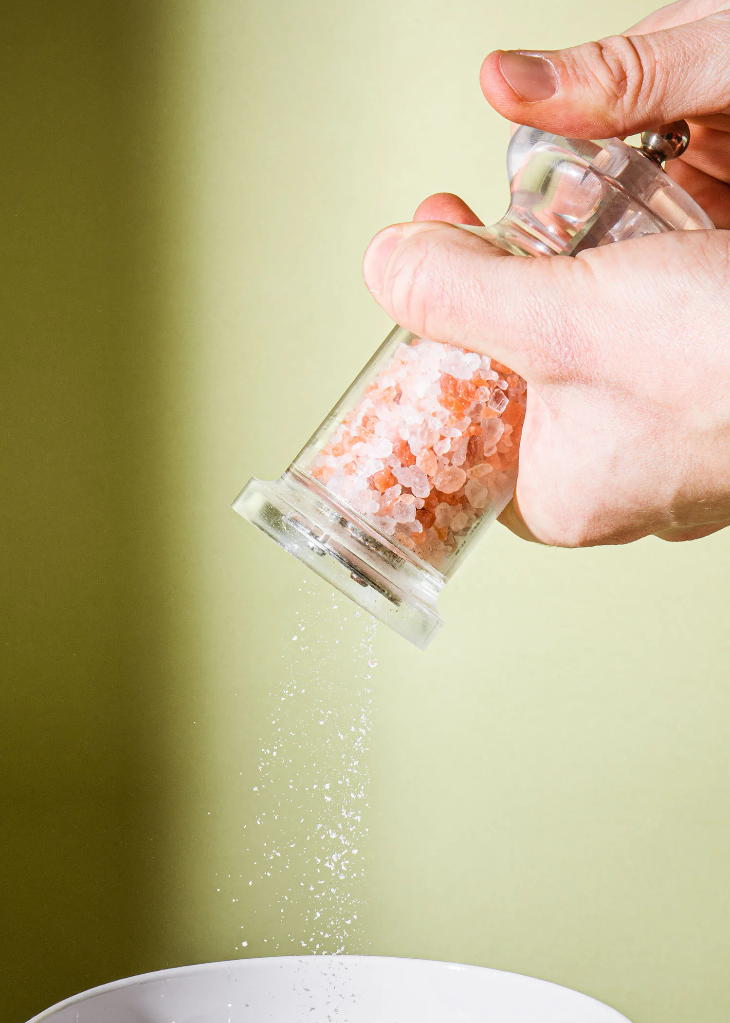 a person is pouring pink salt into a bowl