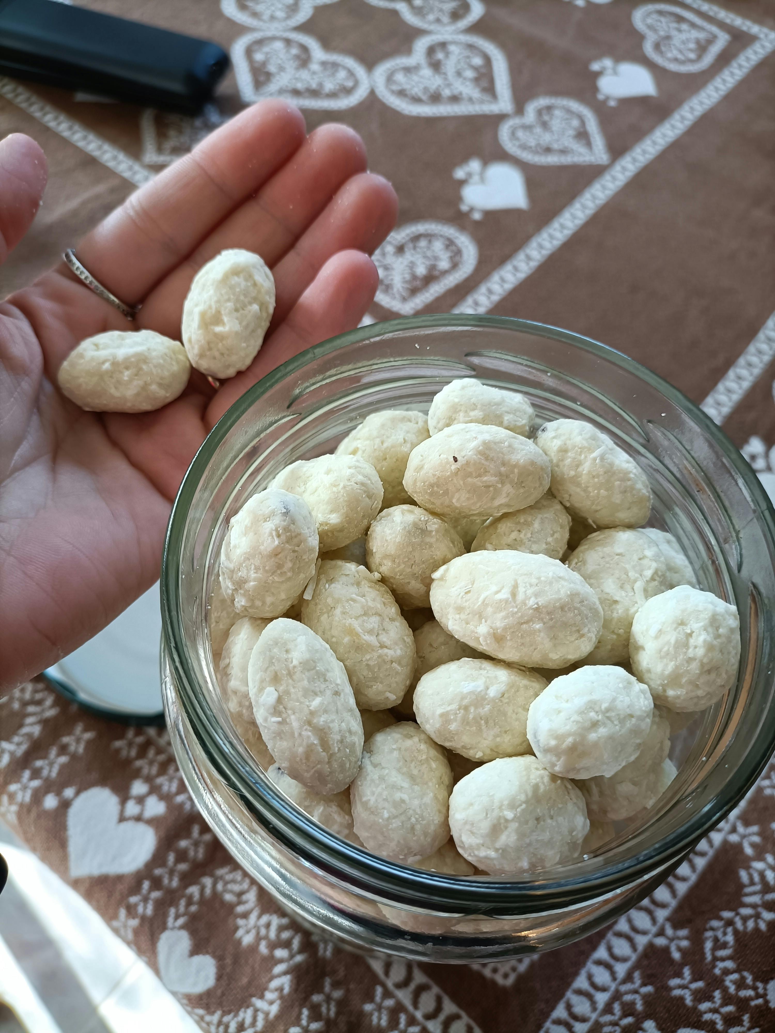 eine Person hält eine Glasschüssel mit weißen Erdnüssen in der Hand