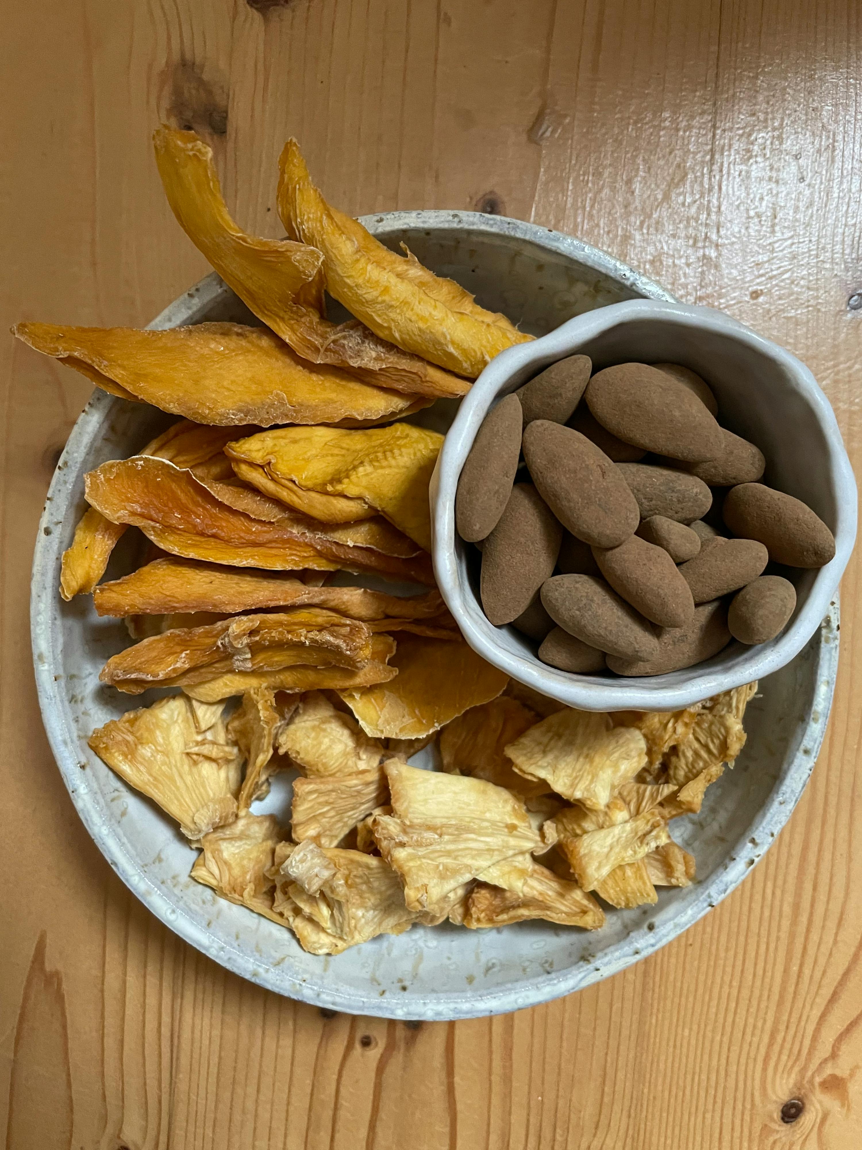 ein Teller mit getrockneten Früchten und Erdnüssen auf einem Holztisch