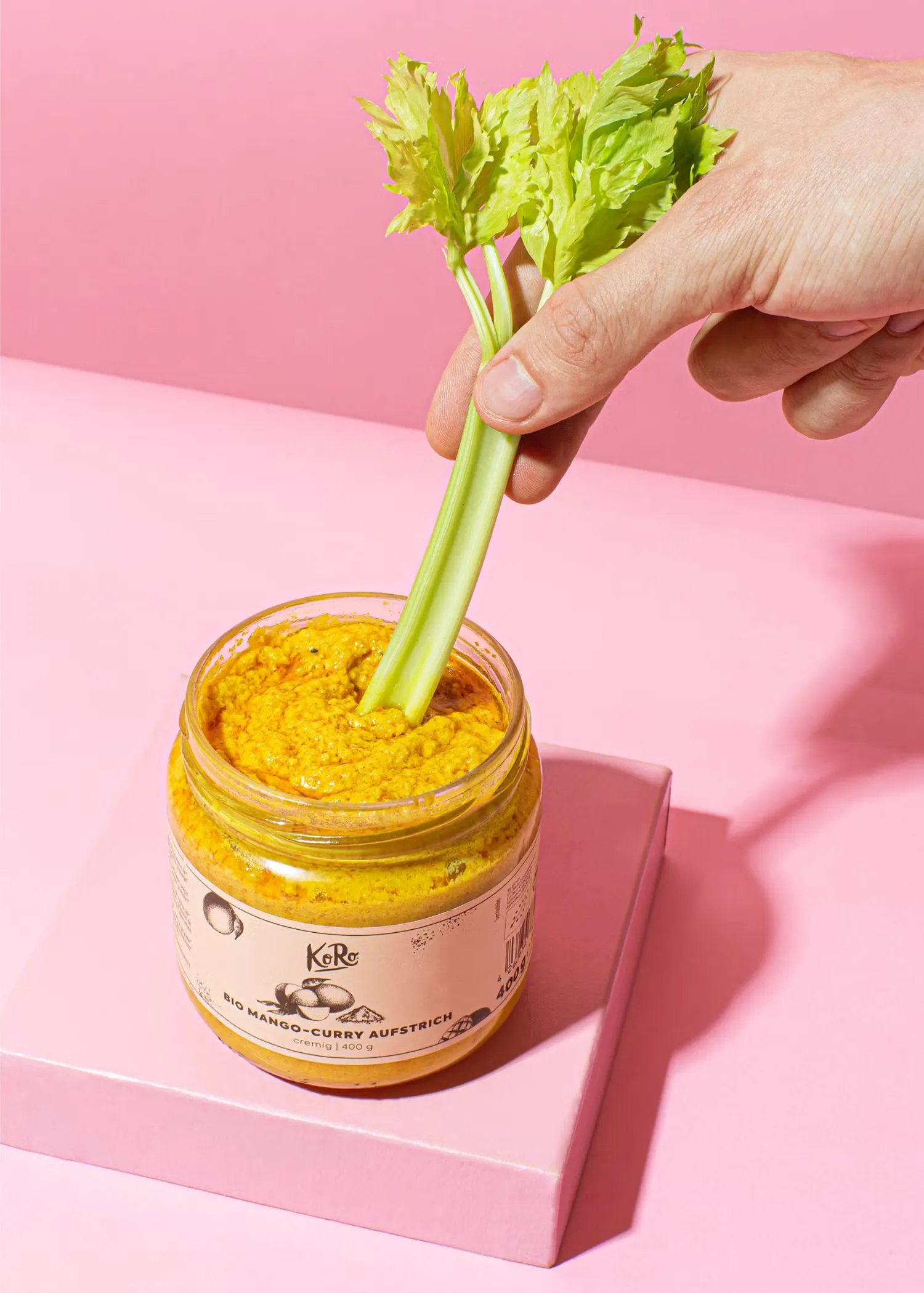 a jar of mango curry sauce with celery sticking out of it