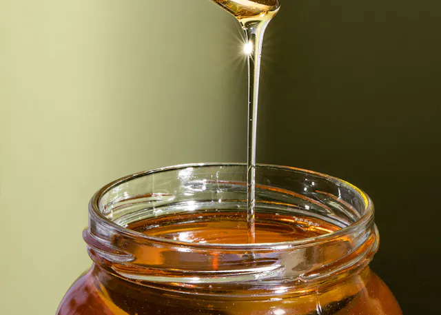 Honig wird in ein Glasgefäß gegossen