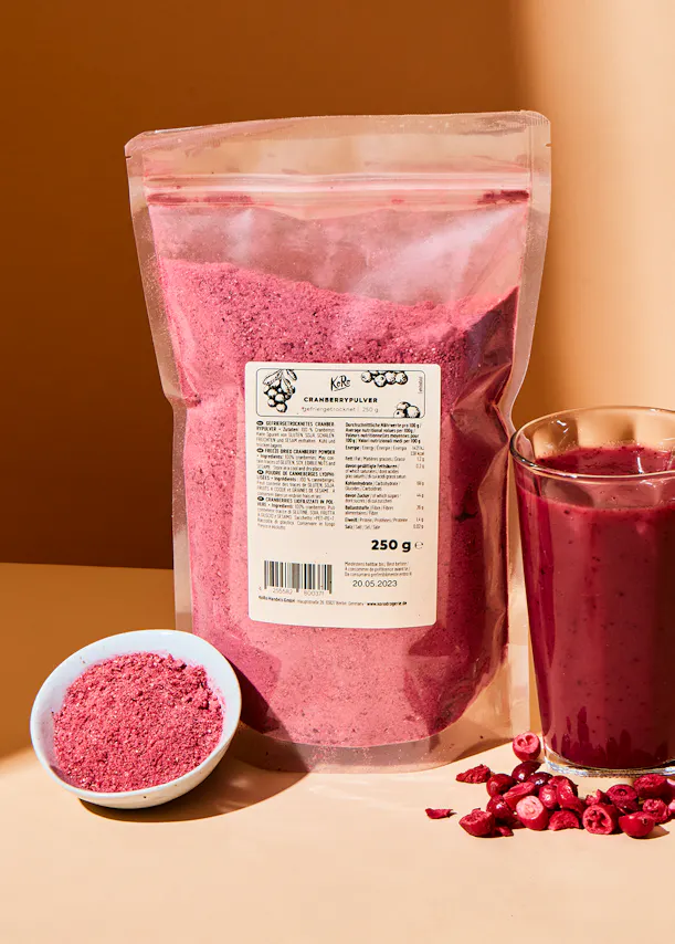un sac de poudre de canneberge est assis à côté d' un verre de smoothie