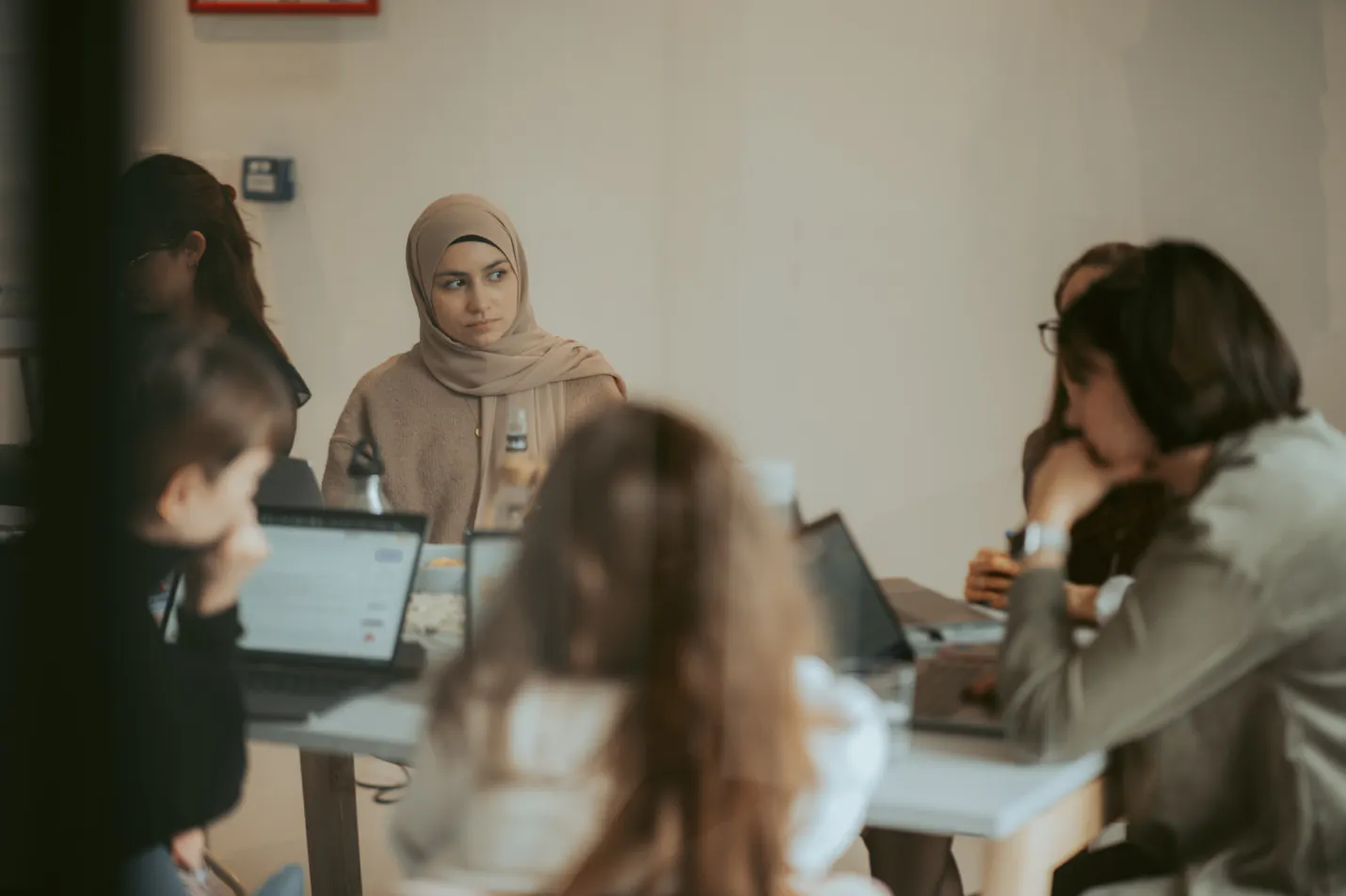 un groupe de femmes est assis autour d' une table avec des ordinateurs portables