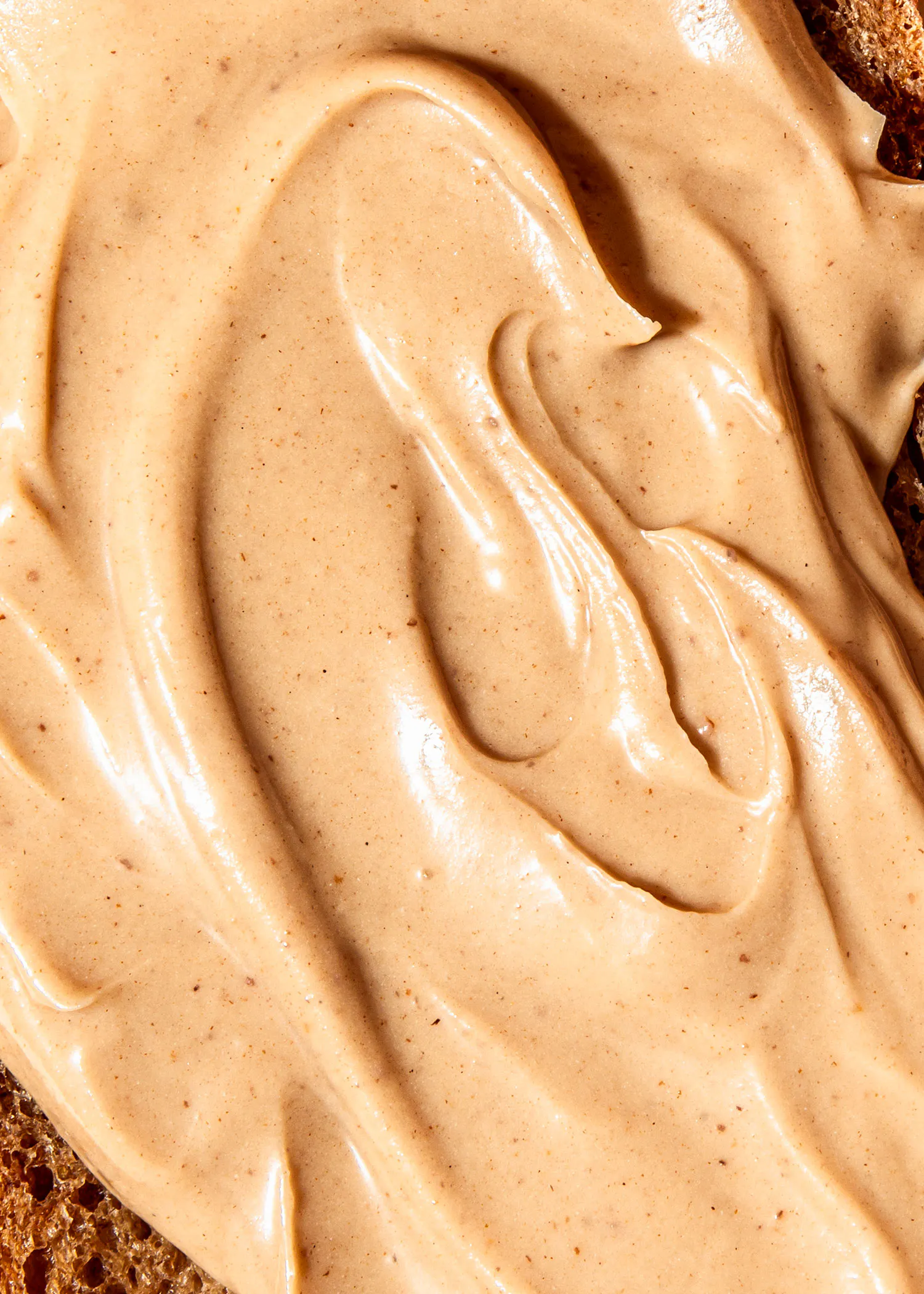 eine Nahaufnahme einer Erdnussbutter auf einem Stück Brot