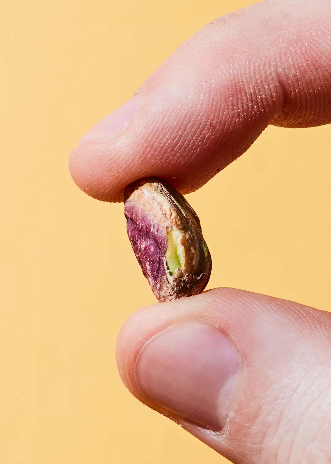 a person is holding a pistachio in their finger