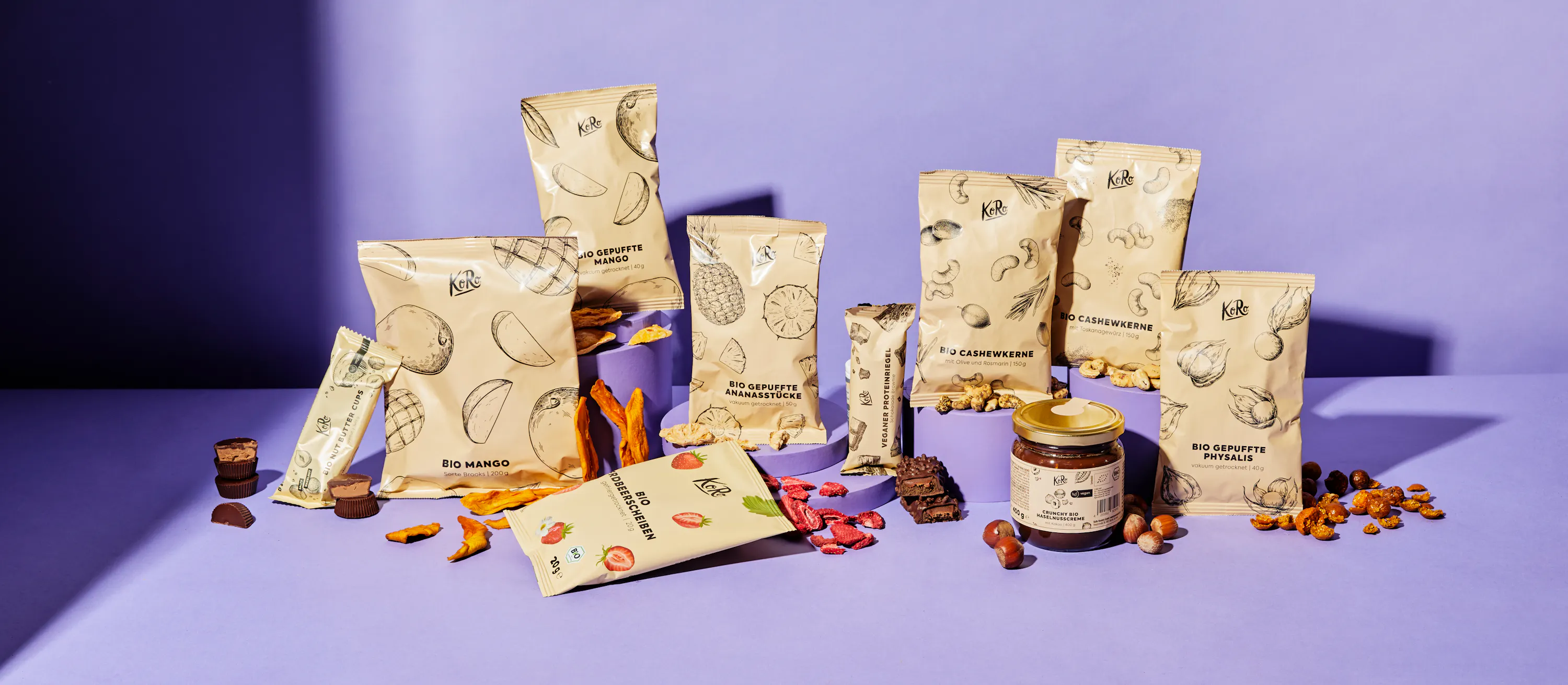 eine Reihe von verpackten Snacks steht auf einem lila Tisch