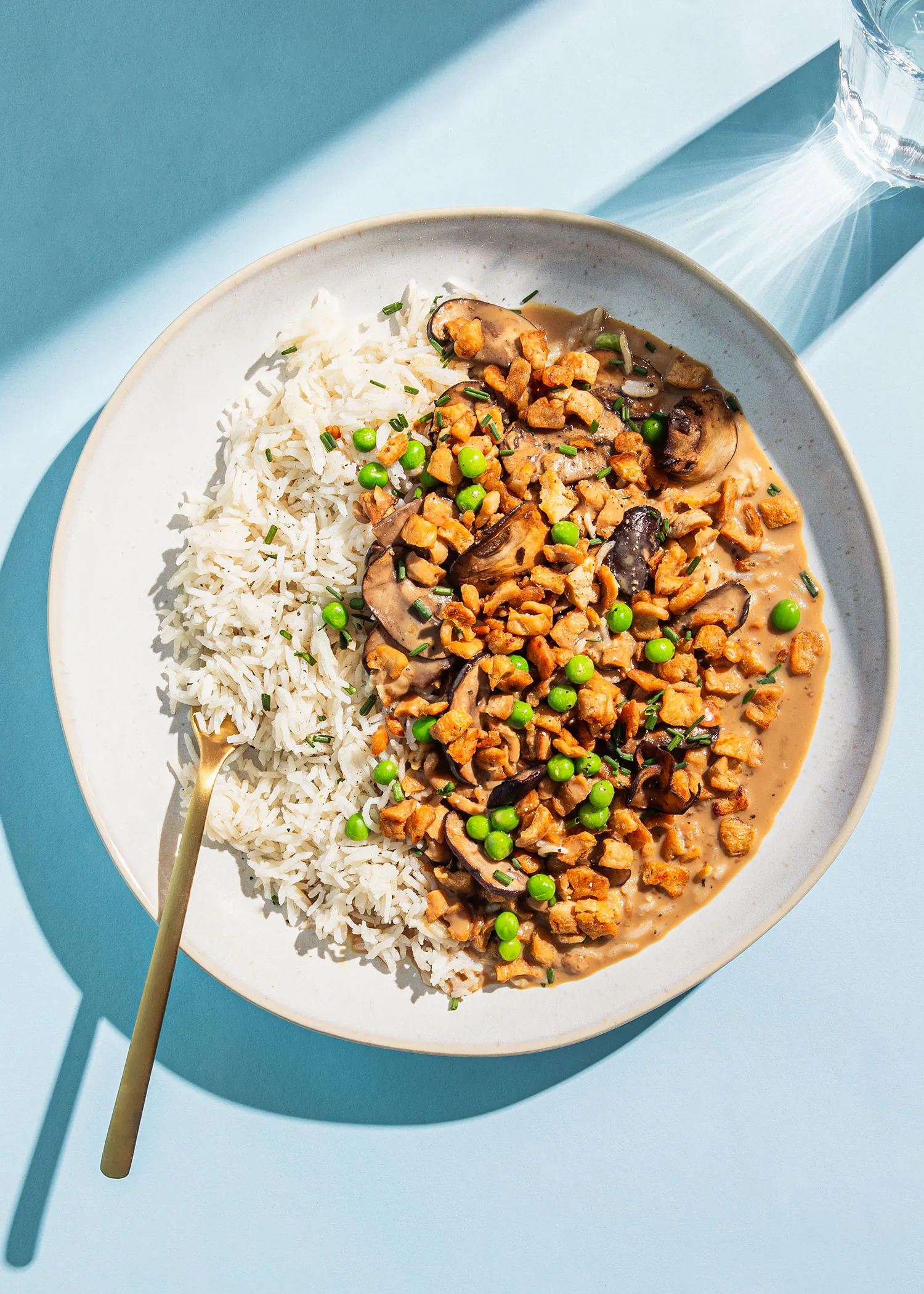 a plate of food with rice mushrooms and peas on a blue surface